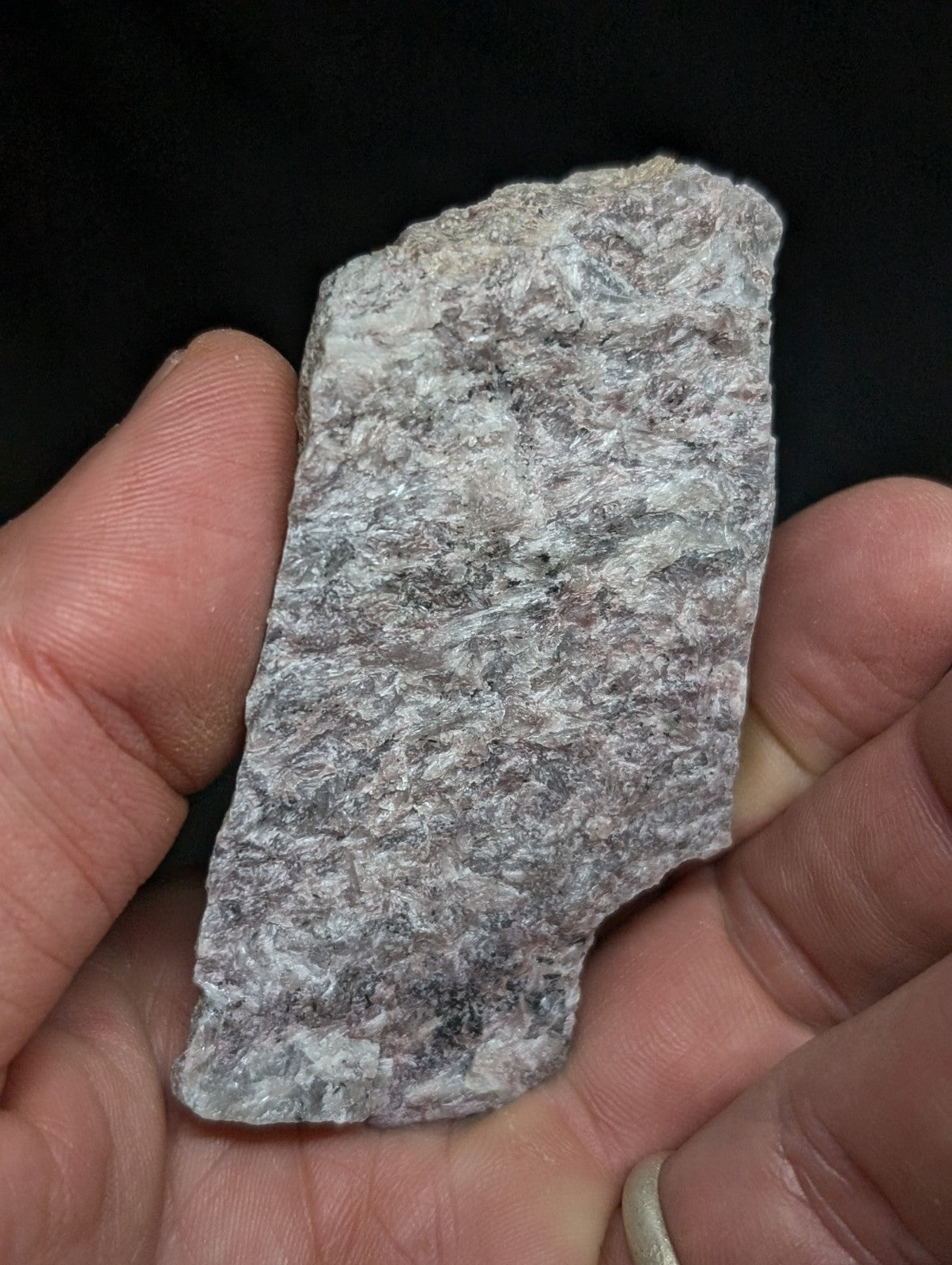 A rough, irregularly shaped gray rock fragment with a mottled texture and subtle white veining.