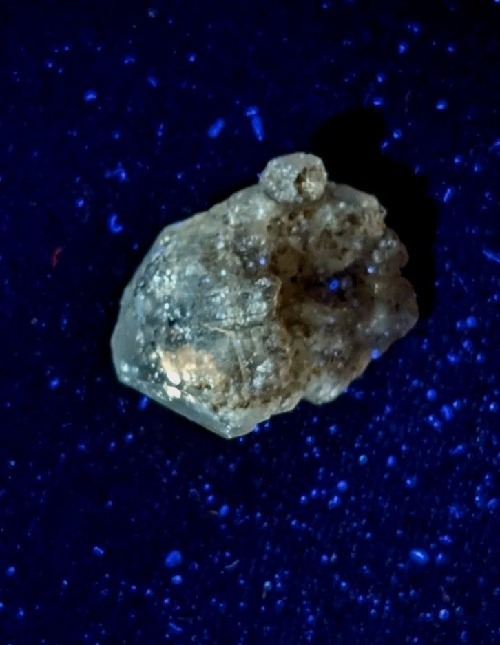 A translucent, irregularly shaped crystal with a rough, textured surface and subtle golden-brown inclusions.