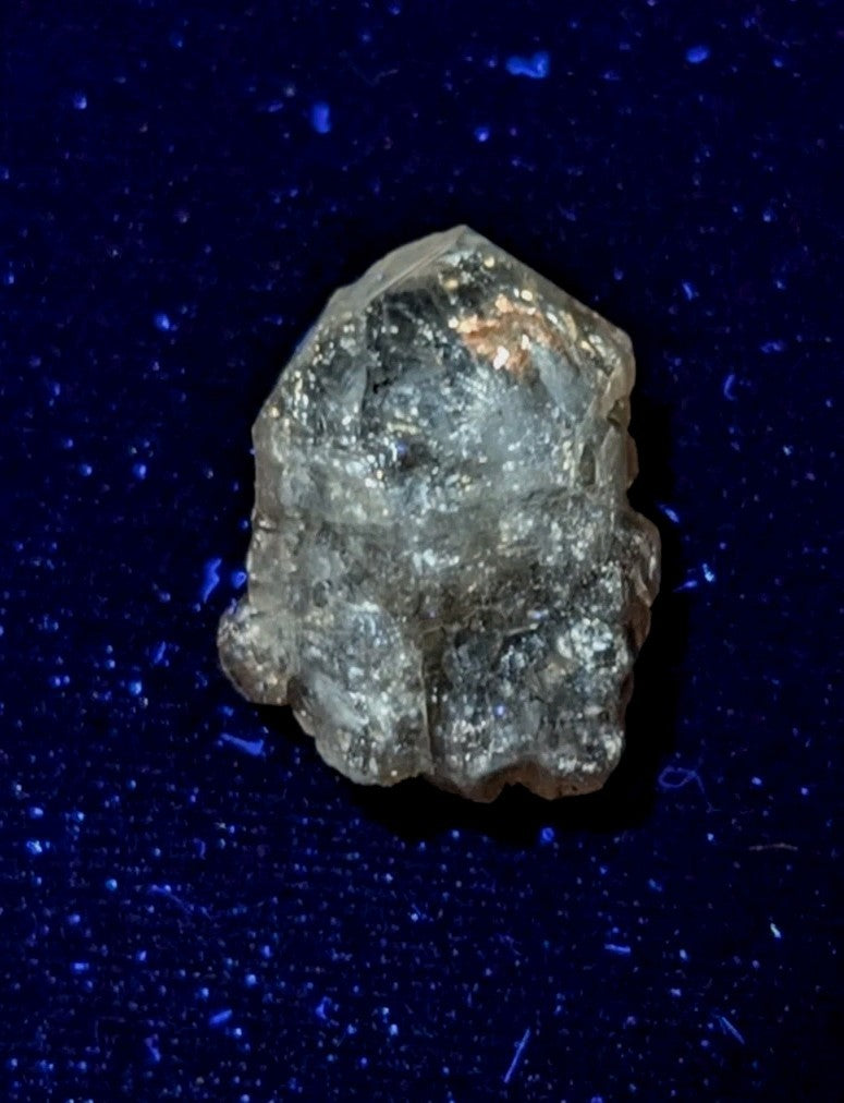 A rough, translucent crystal with a faceted surface and subtle golden inclusions.