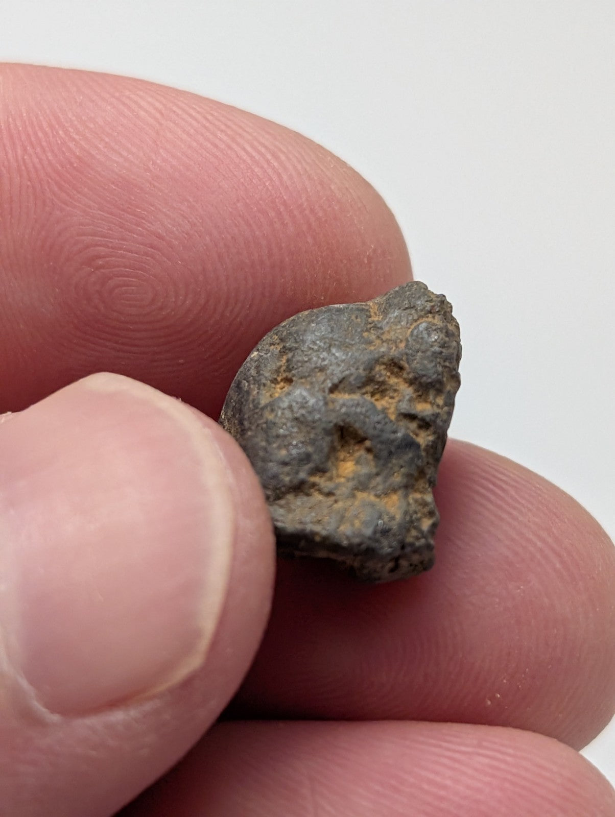 A weathered dark gray metallic placer rutile fragment with orange rust patches from magnet cove arkansas old stock set of 25