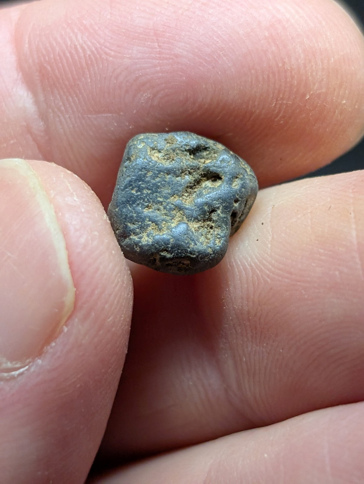 A weathered, irregularly shaped metallic object with a dark greenish-blue patina and patches of lighter corrosion.