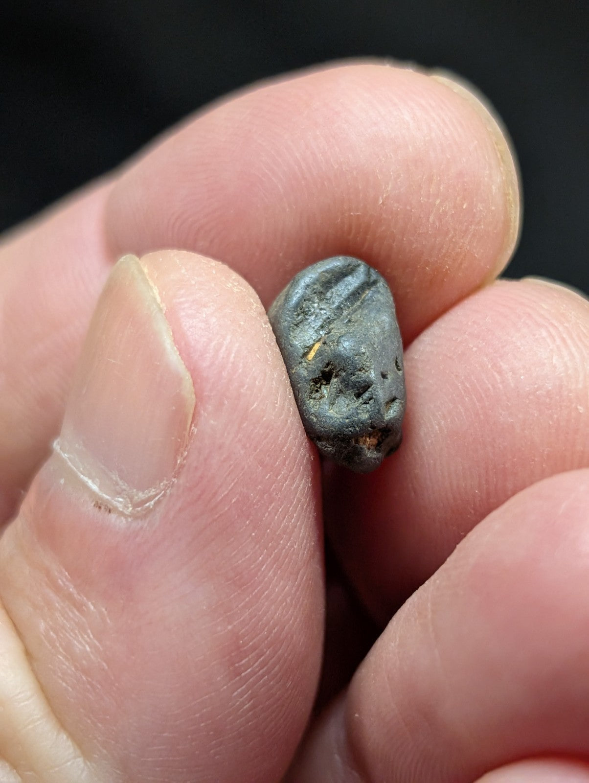 A dark gray, irregularly shaped stone with a rough texture and subtle striations.