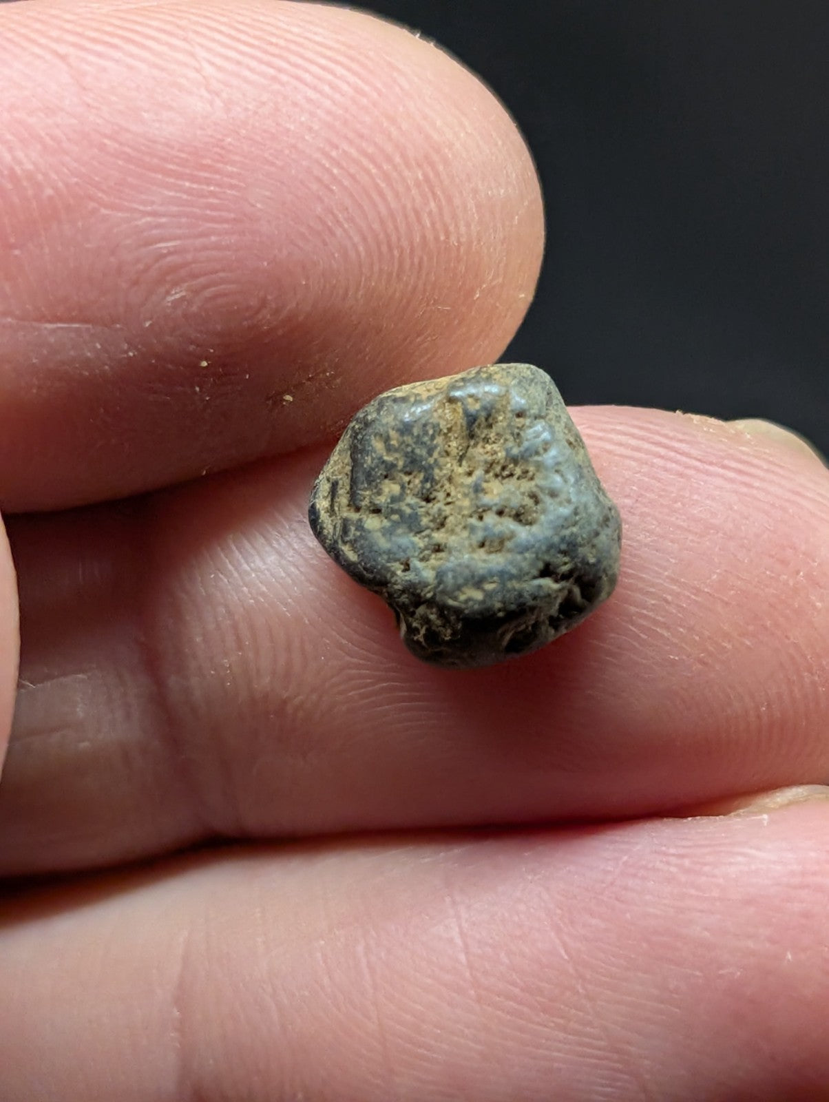 A weathered, irregularly shaped ancient coin with a greenish patina and visible surface wear.