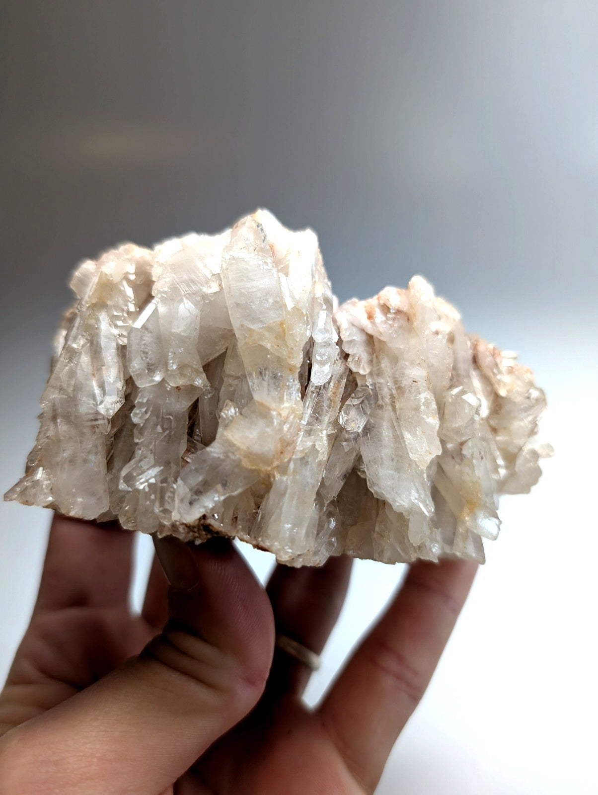 A translucent, milky white faden quartz crystal cluster from montgomery county, arkansas, held in a hand