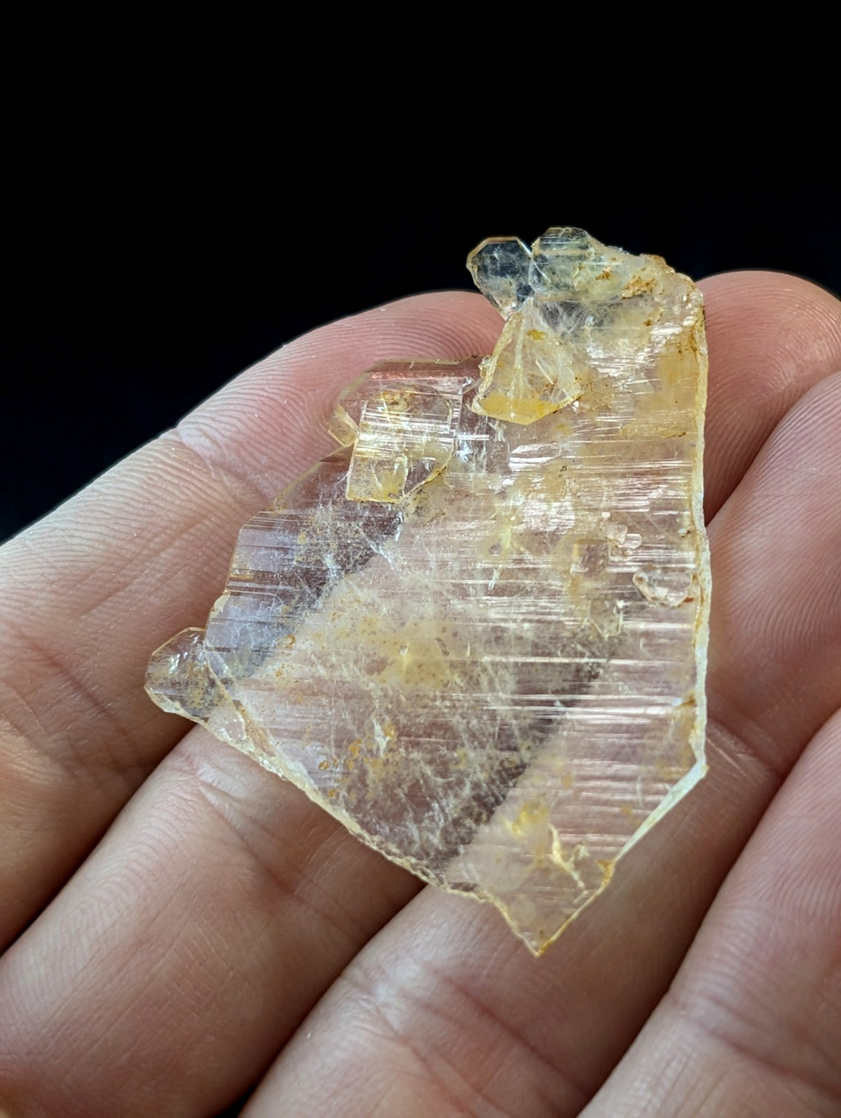 A translucent yellowish crystal with visible striations and a rough, jagged edge.