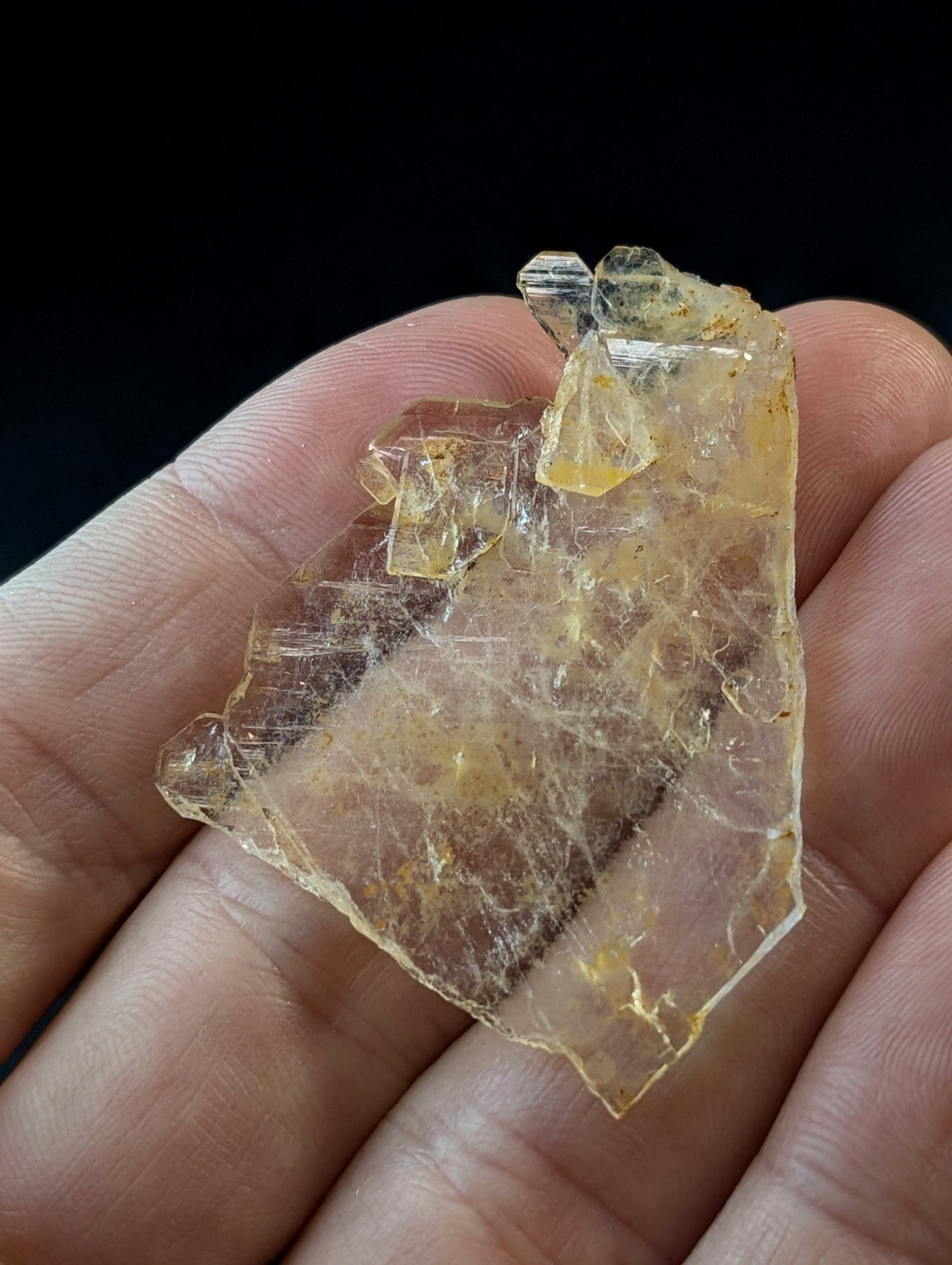 A translucent yellowish crystal specimen with visible internal striations and a rough, jagged surface.