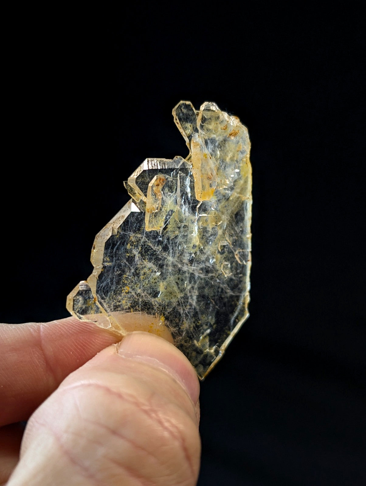 A translucent yellowish crystal with a rough, jagged surface and visible internal web-like inclusions.