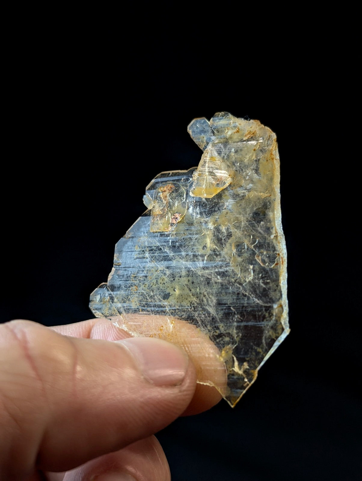 A translucent, amber-hued crystal fragment with visible internal striations and a rough, jagged edge.