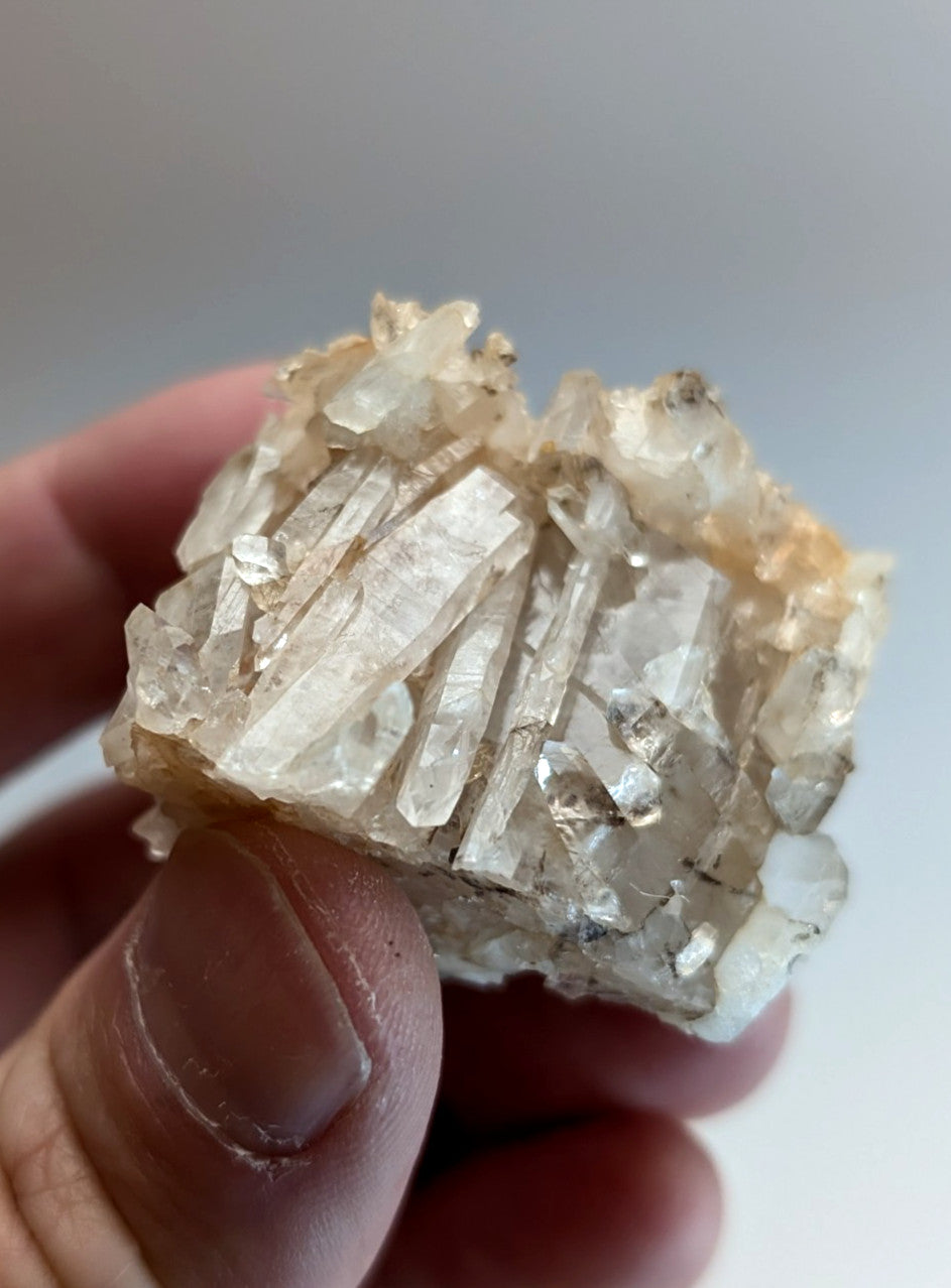 A cluster of translucent clear quartz crystals with golden brown veining on a rough natural matrix from montgomery county arkansas