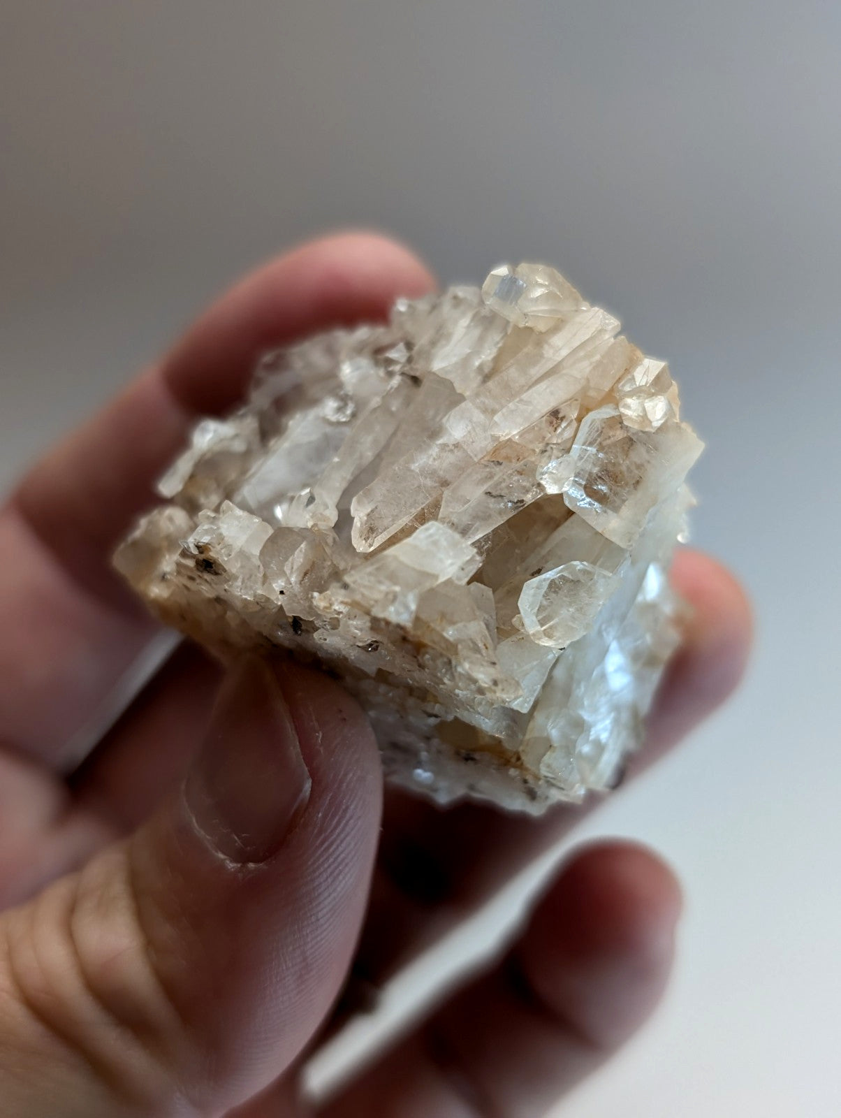 A translucent crystalline faden wheel quartz crystal cluster with clear and cloudy facets held in hand from Arkansas usa