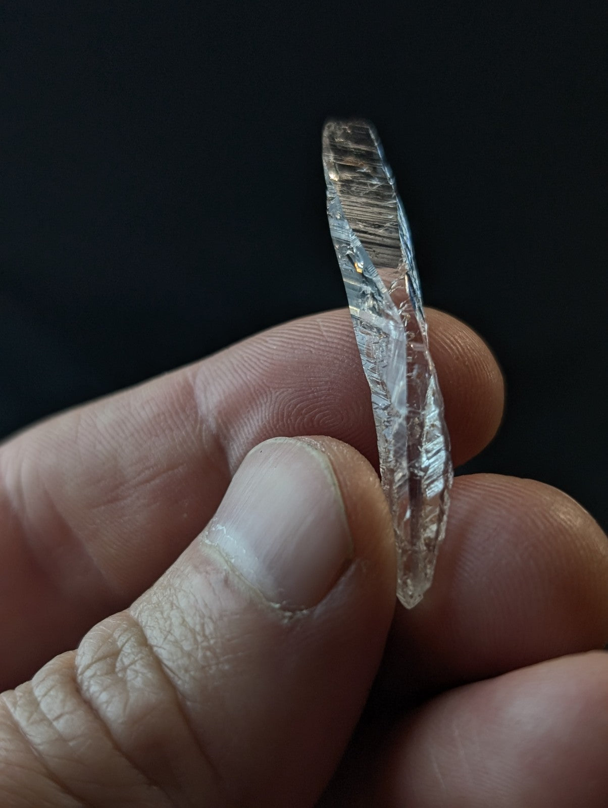 A clear, transparent quartz crystal with a natural, twisted internal structure and visible inclusions.