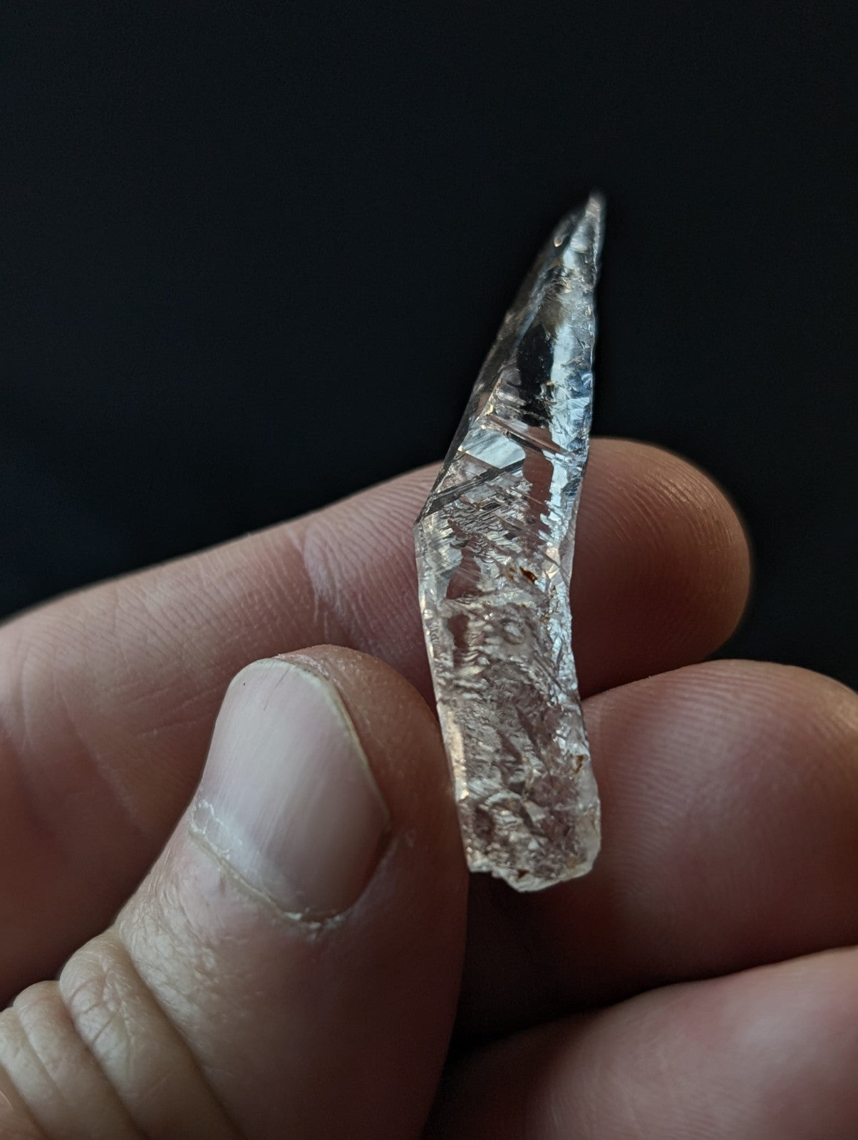 A clear, faceted raw diamond held in a hand.