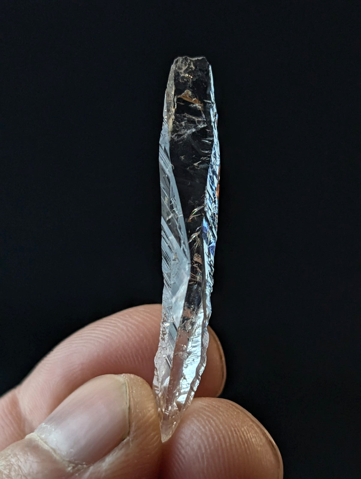 A clear, faceted quartz crystal with natural internal inclusions and a pointed tip.