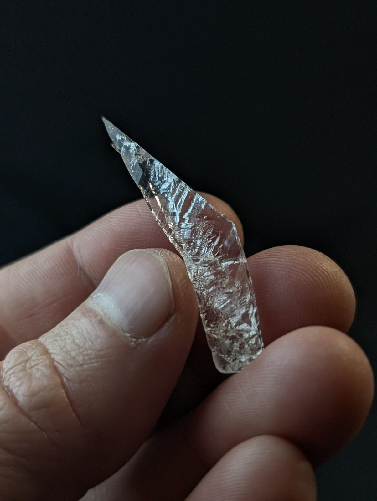A translucent, clear crystal with a sharp point and intricate internal patterns.