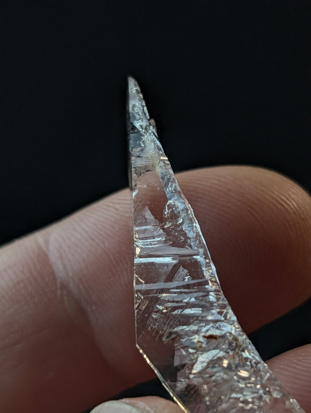 A clear, faceted quartz crystal with a pointed tip and visible internal striations.