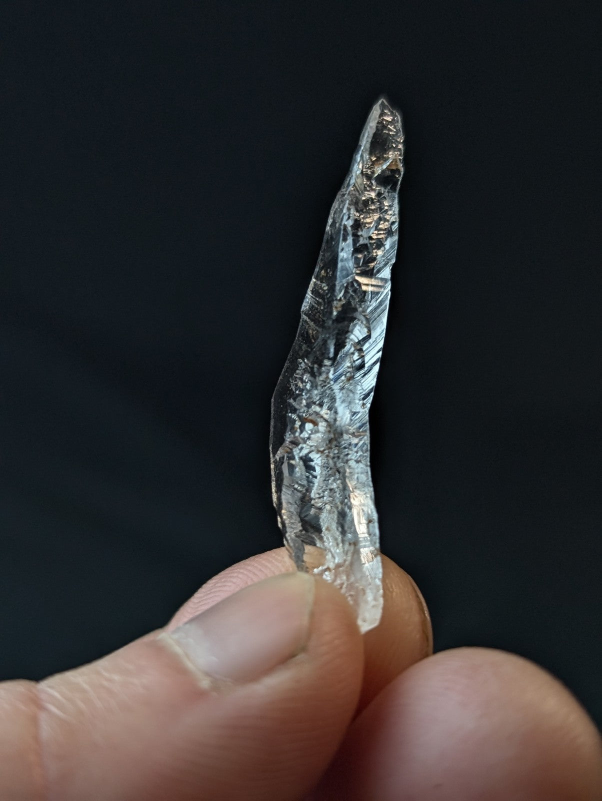 A translucent, clear quartz crystal with visible internal striations and a pointed tip.