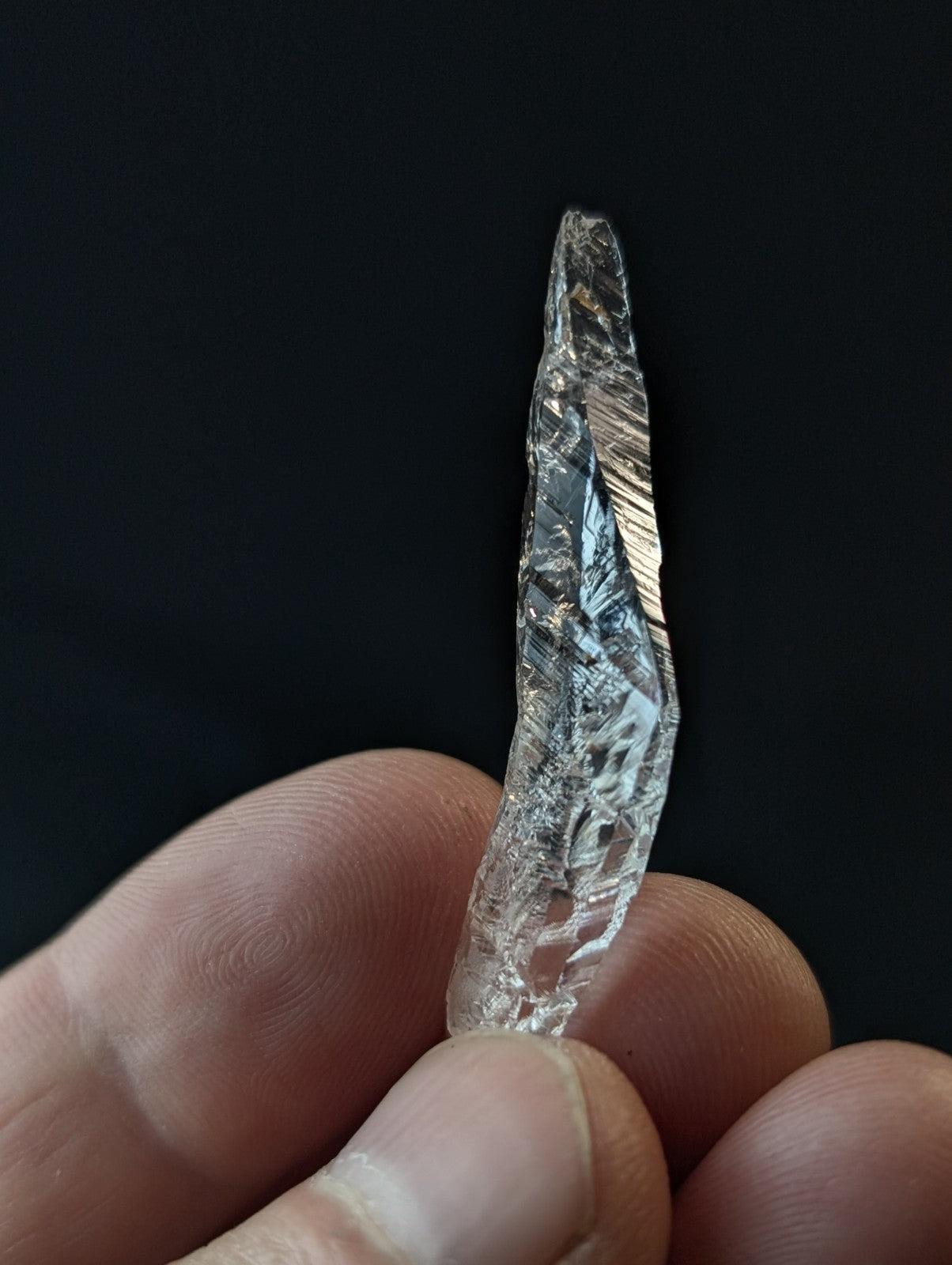 A clear, faceted crystal with a pointed tip and intricate internal patterns.