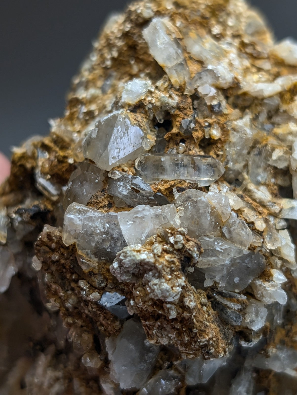 A cluster of translucent clear quartz crystals with cookeite on a rough brown matrix from saline county Arkansas