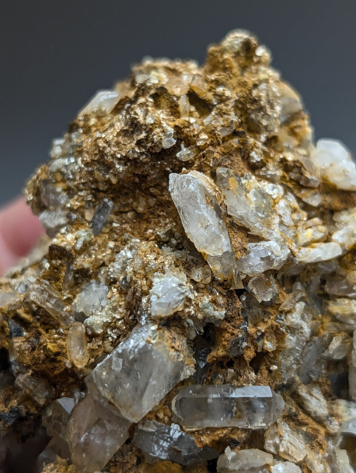 A cluster of translucent quartz crystals growing on a golden mineral-rich cookeite conglomerate from Arkansas