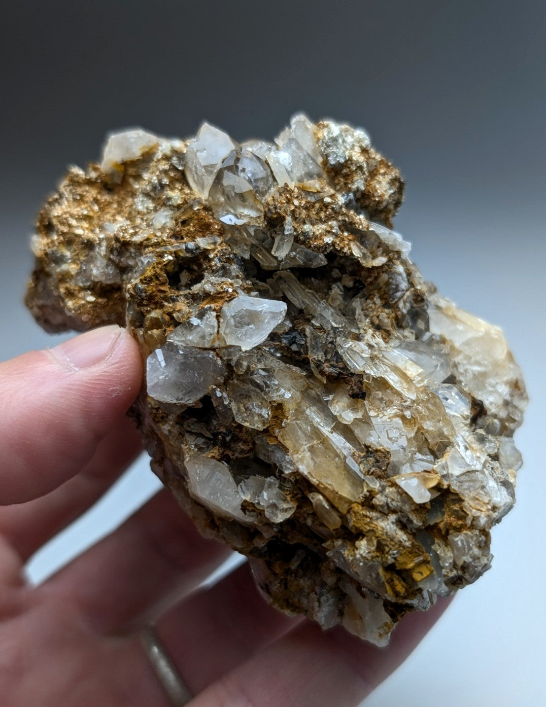A hand holds a rare natural quartz and cookeite conglomerate with clear to pale yellow crystals from Saline County Arkansas