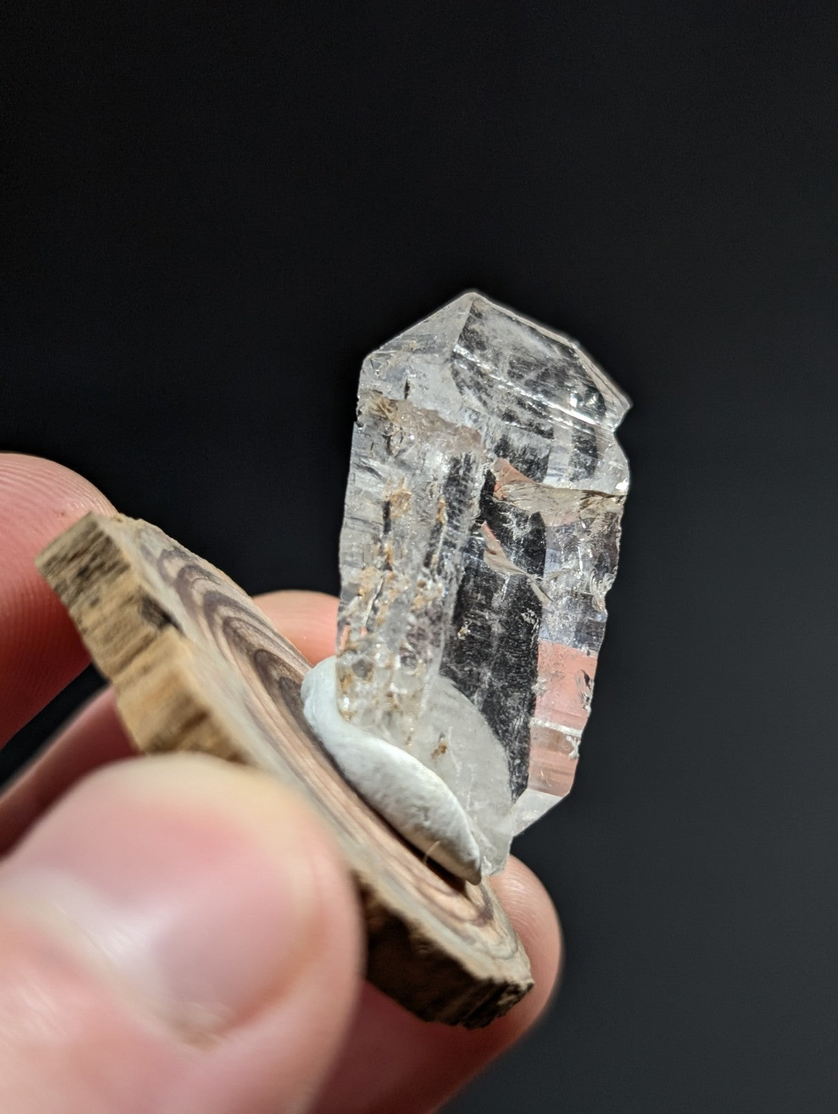A clear, faceted quartz crystal with natural inclusions and a slightly rough-edged base.