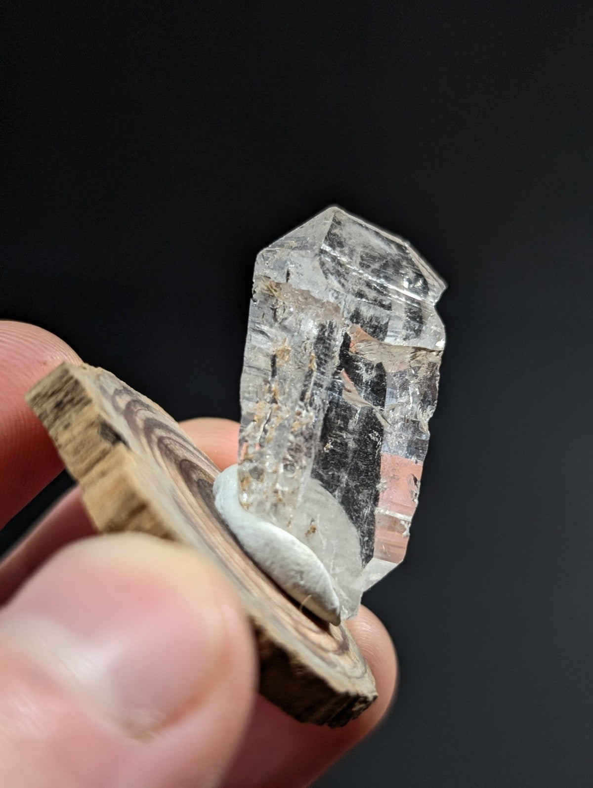 A clear, faceted quartz crystal with natural inclusions and a slightly rough-edged base.