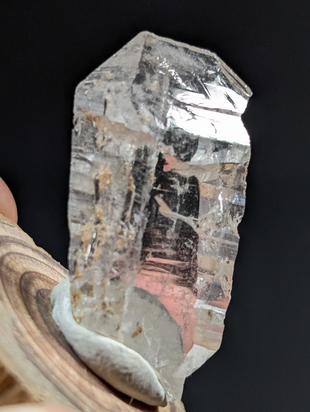 A translucent, clear quartz crystal with natural inclusions and a rough, faceted surface.
