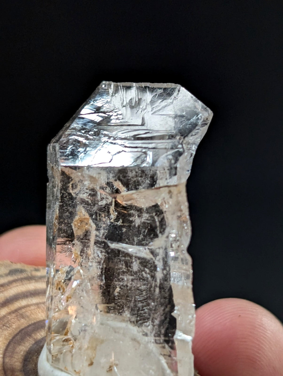 A translucent, clear quartz crystal with a rough, faceted top and internal inclusions.