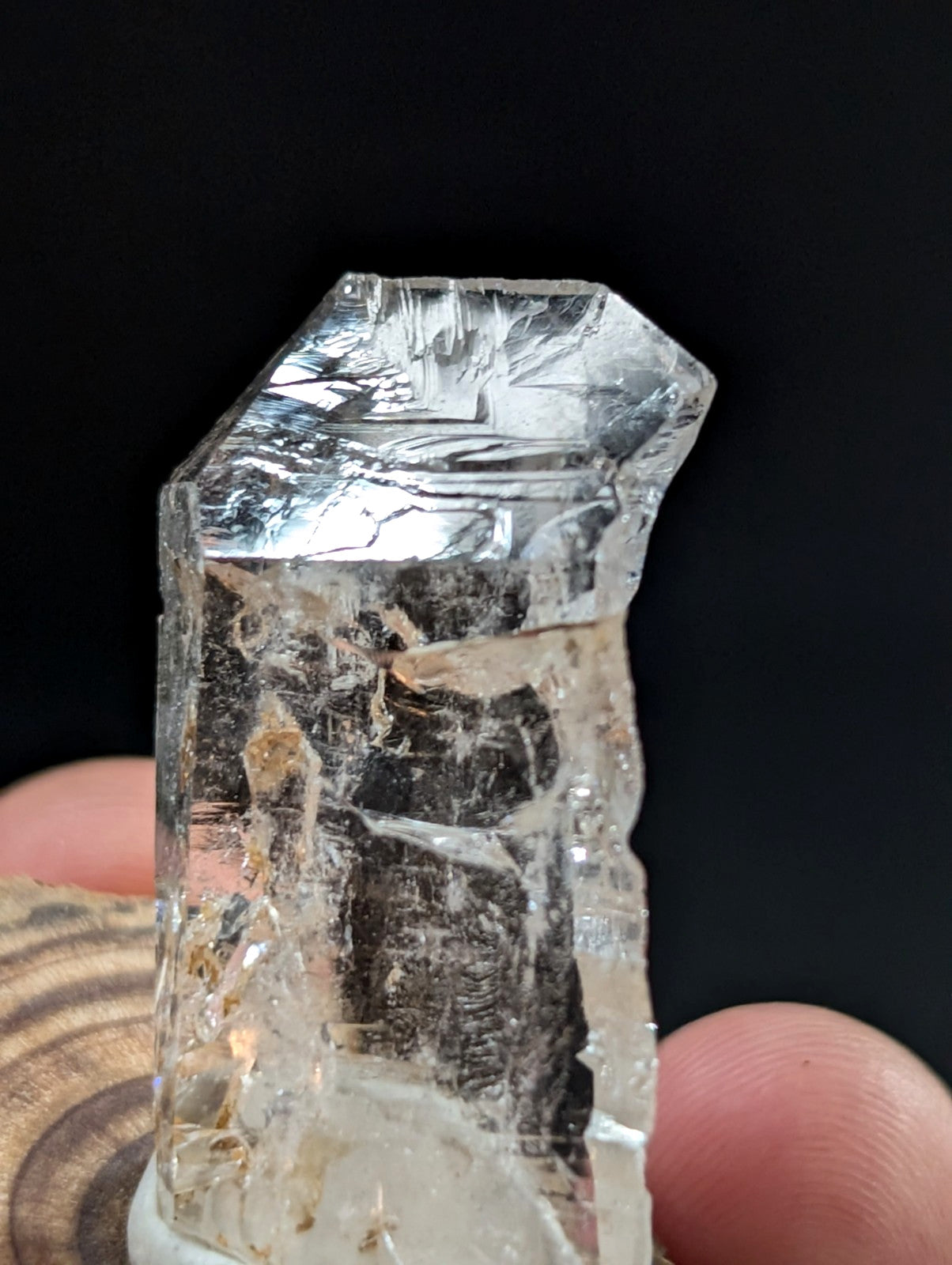 A translucent, clear quartz crystal with a rough, faceted top and internal inclusions.