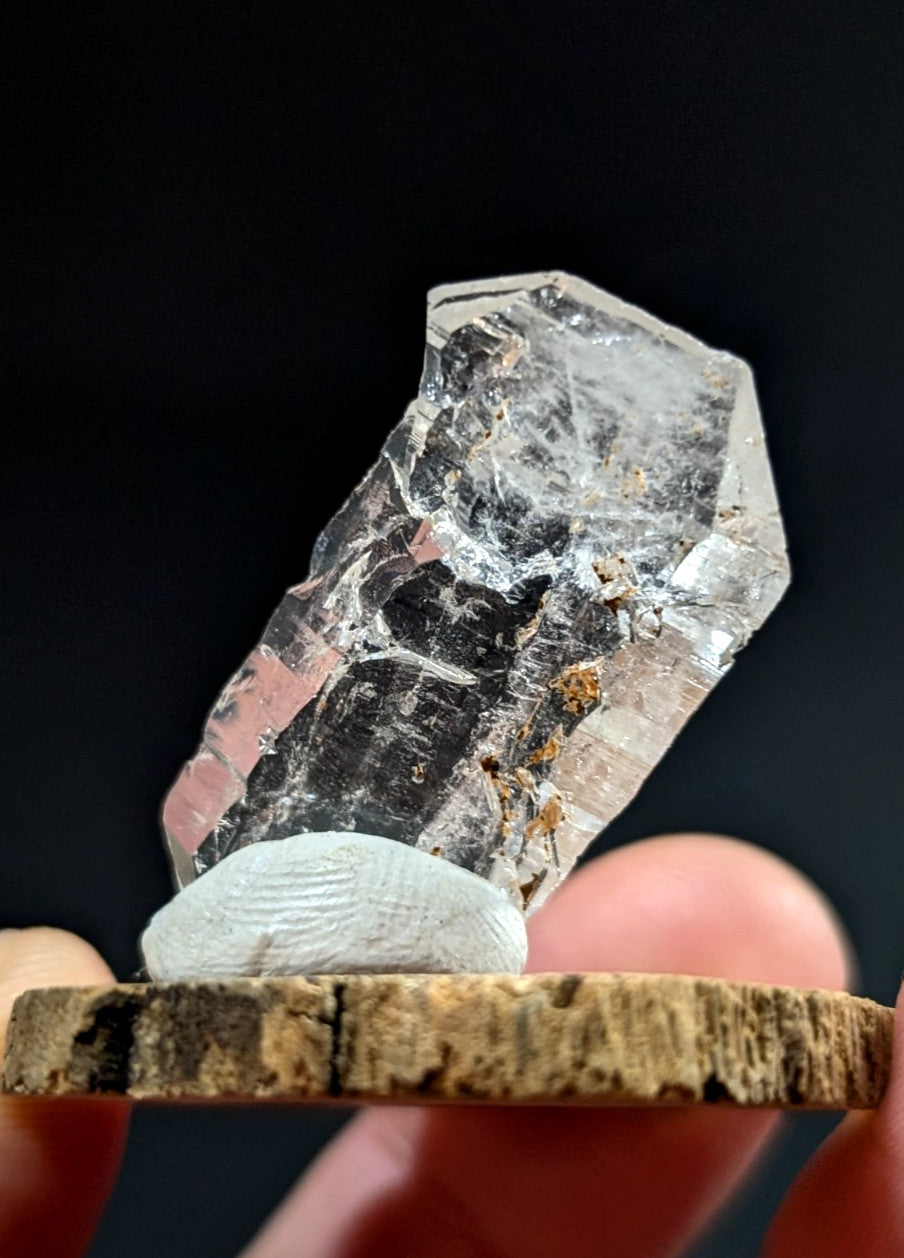A clear, faceted quartz crystal with natural inclusions and a rough-edged base.