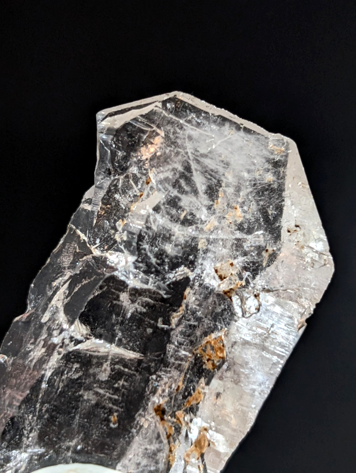 A translucent, faceted quartz crystal with natural inclusions and a mix of clear and darkened sections.