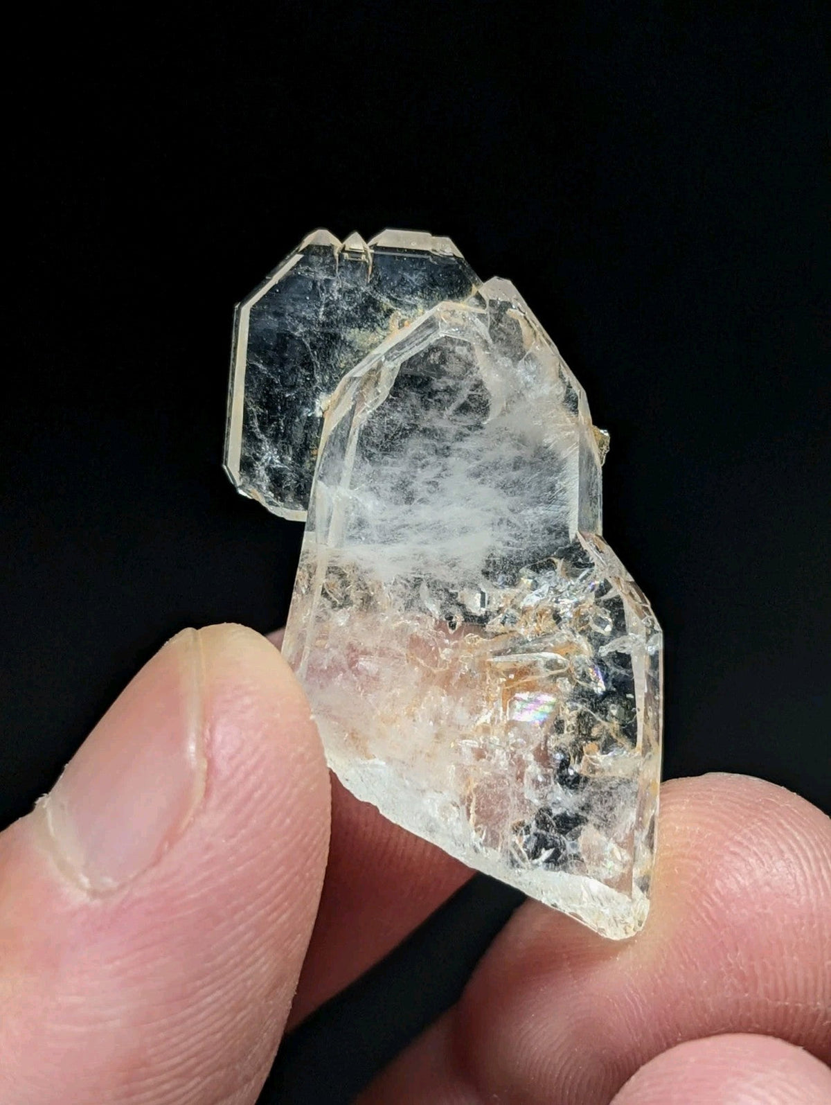 A translucent, clear quartz crystal cluster with a faceted and jagged surface.