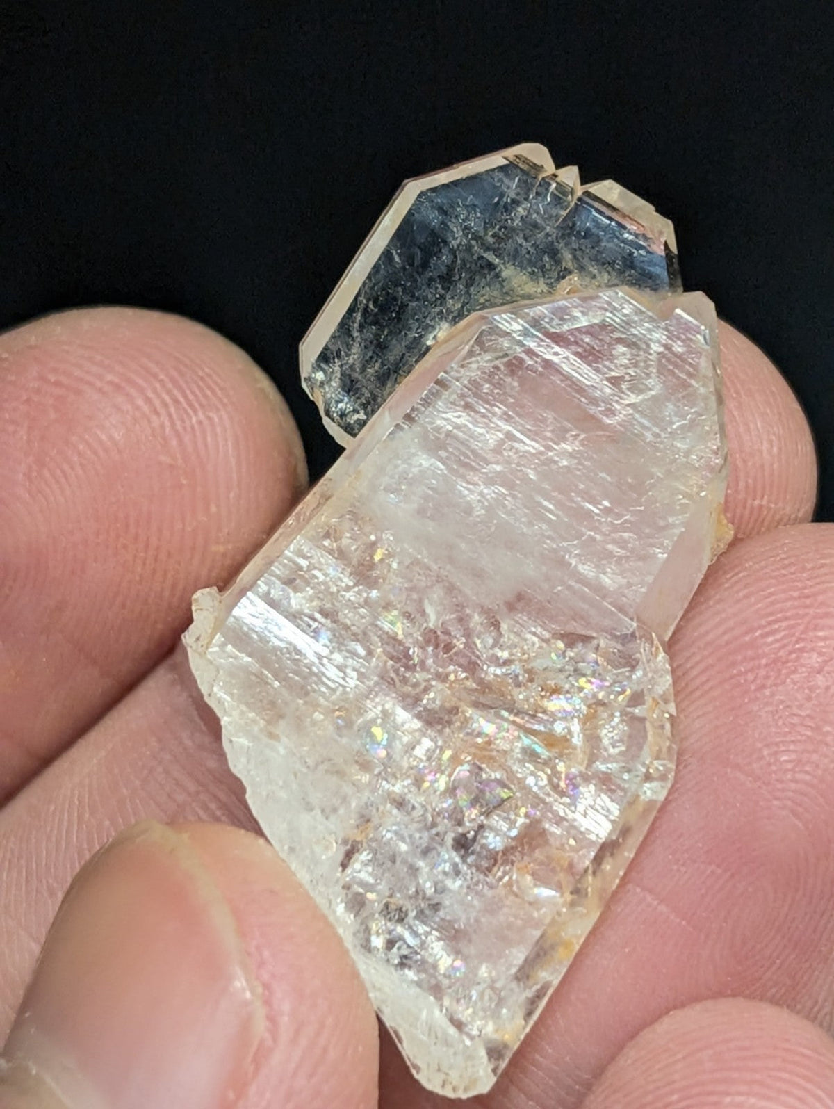 A translucent, faceted quartz crystal with a subtle iridescent sheen and natural striations.
