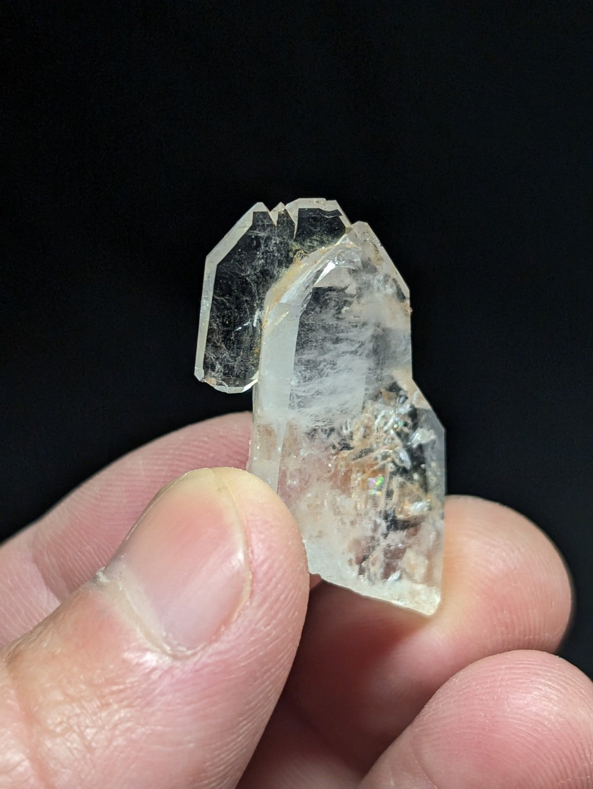 A translucent, clear quartz crystal with a faceted and jagged surface.