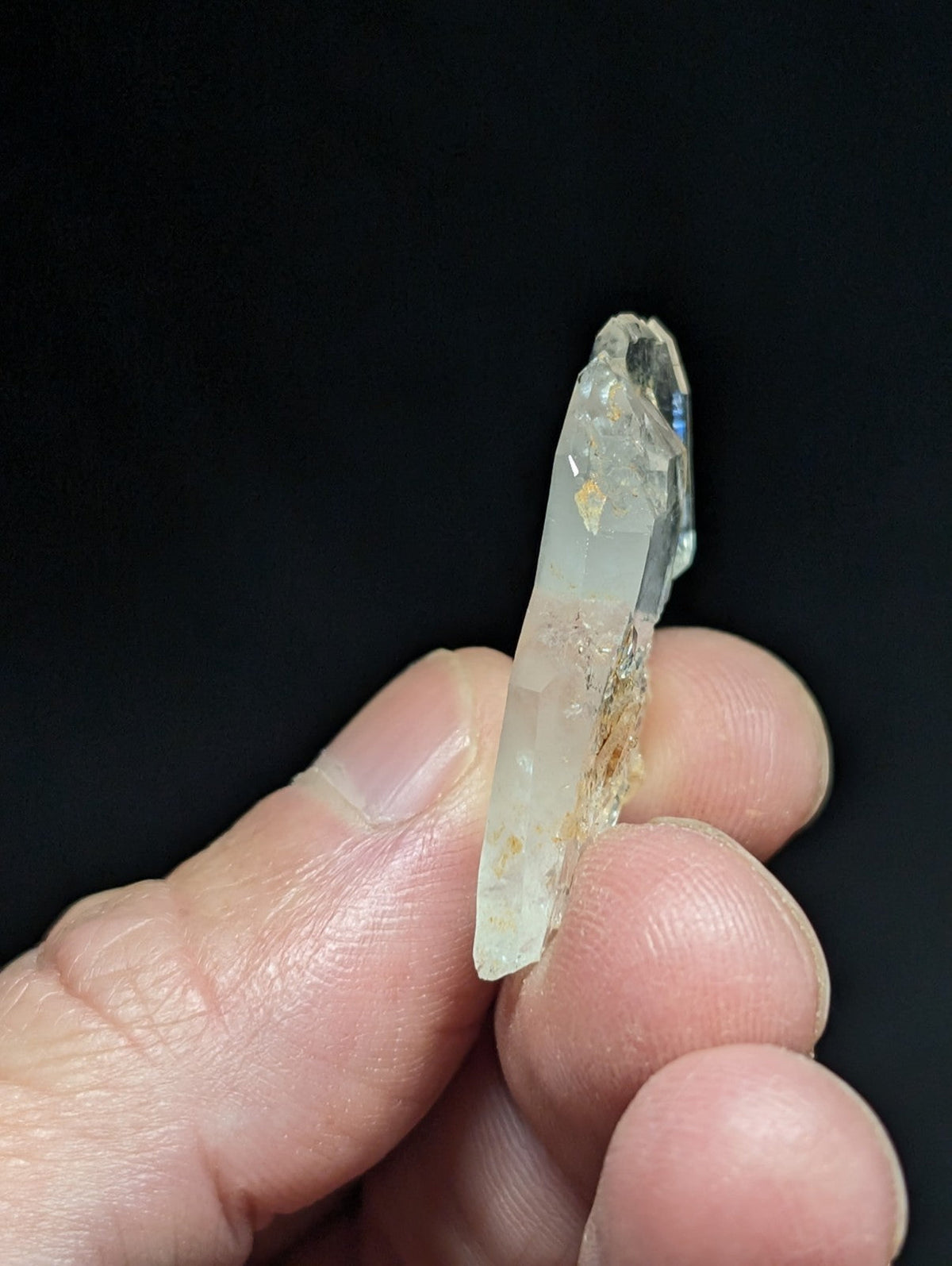A translucent, pale quartz crystal with a pointed tip and natural inclusions.
