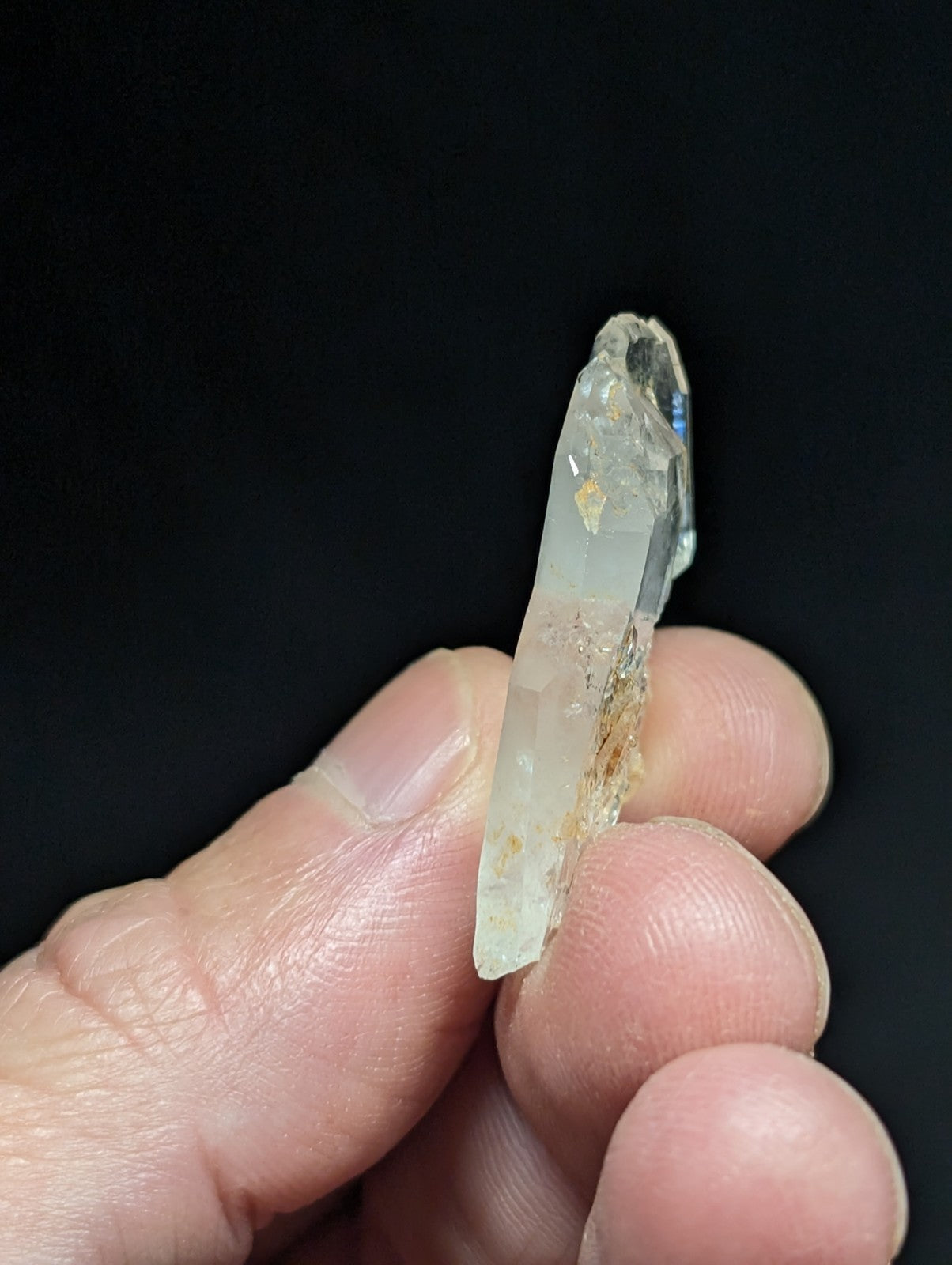 A translucent, pale quartz crystal with a pointed tip and natural inclusions.
