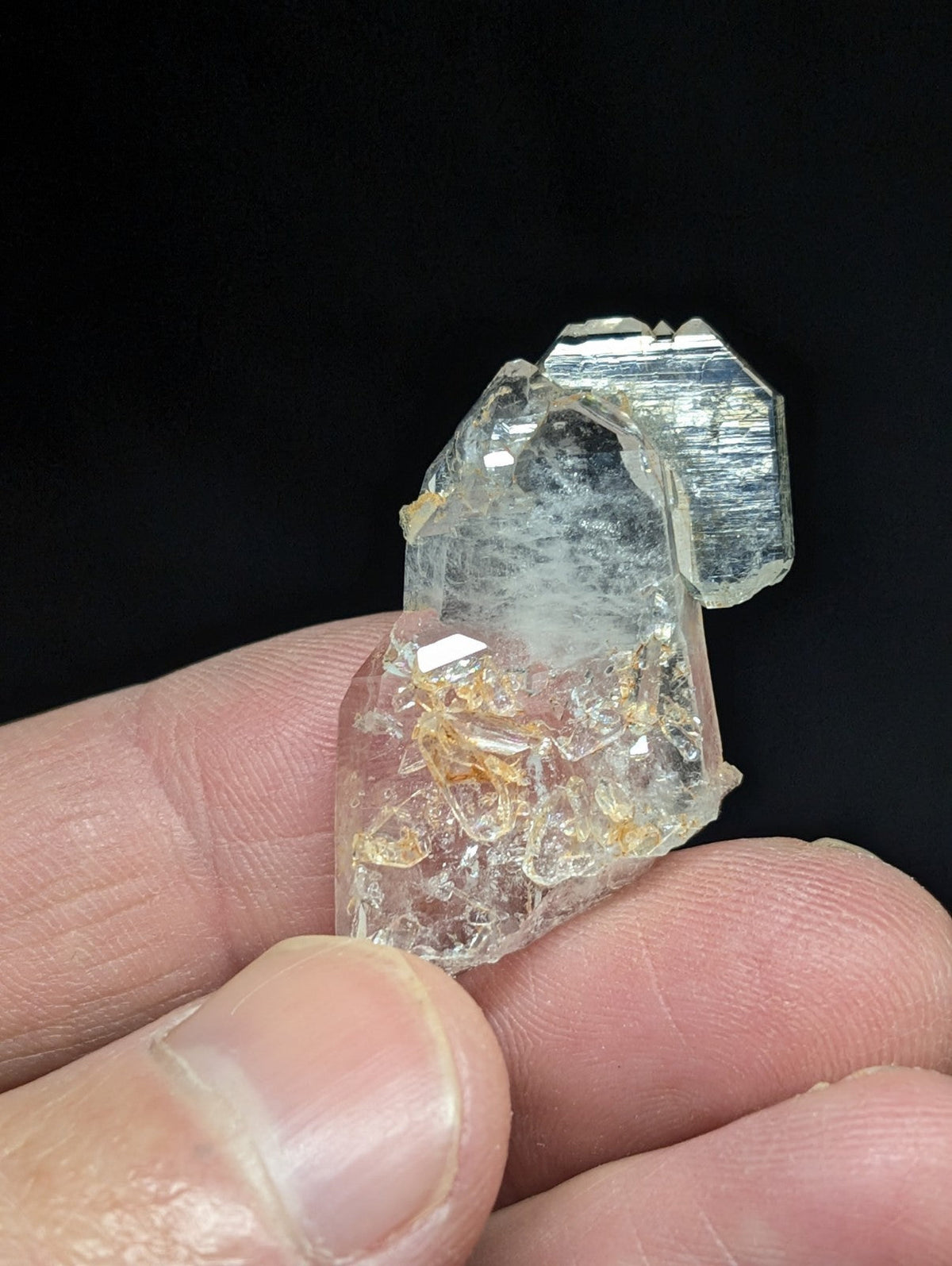 A translucent, clear quartz crystal with golden inclusions and a faceted top.