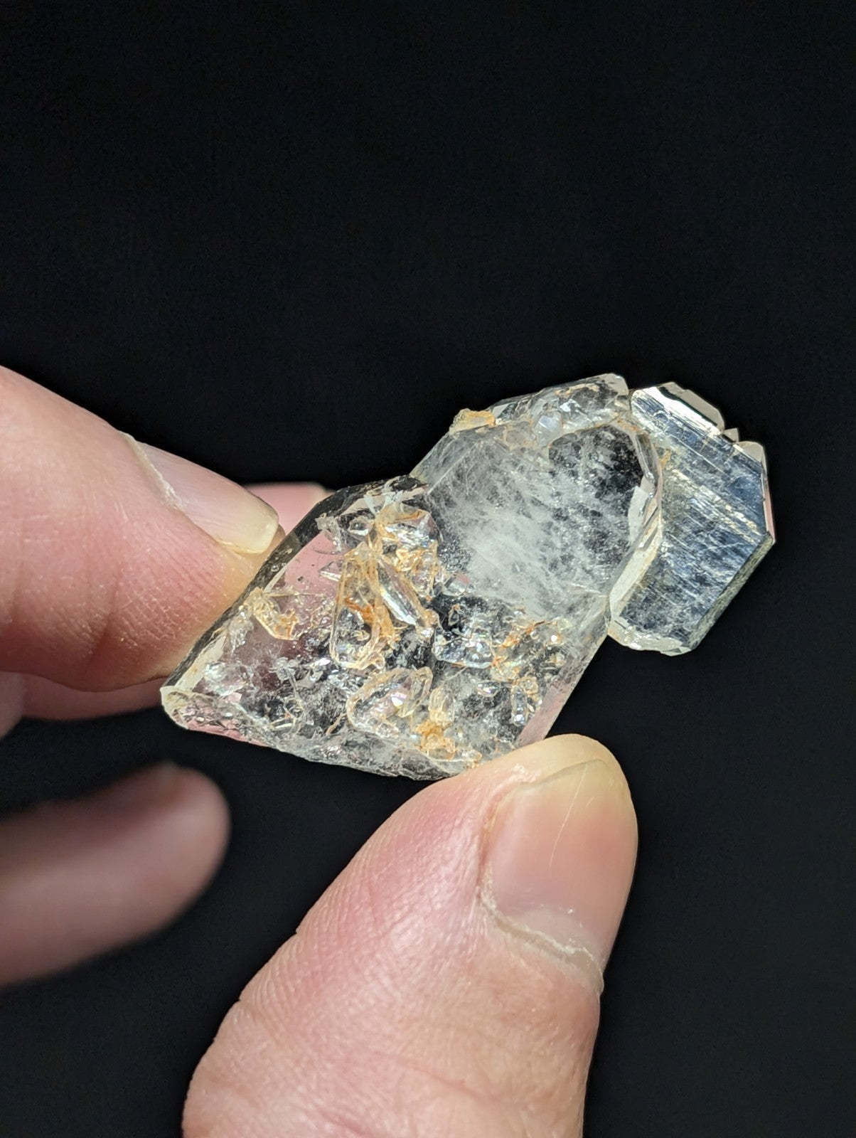 A translucent, clear quartz crystal with subtle golden inclusions and a faceted surface.