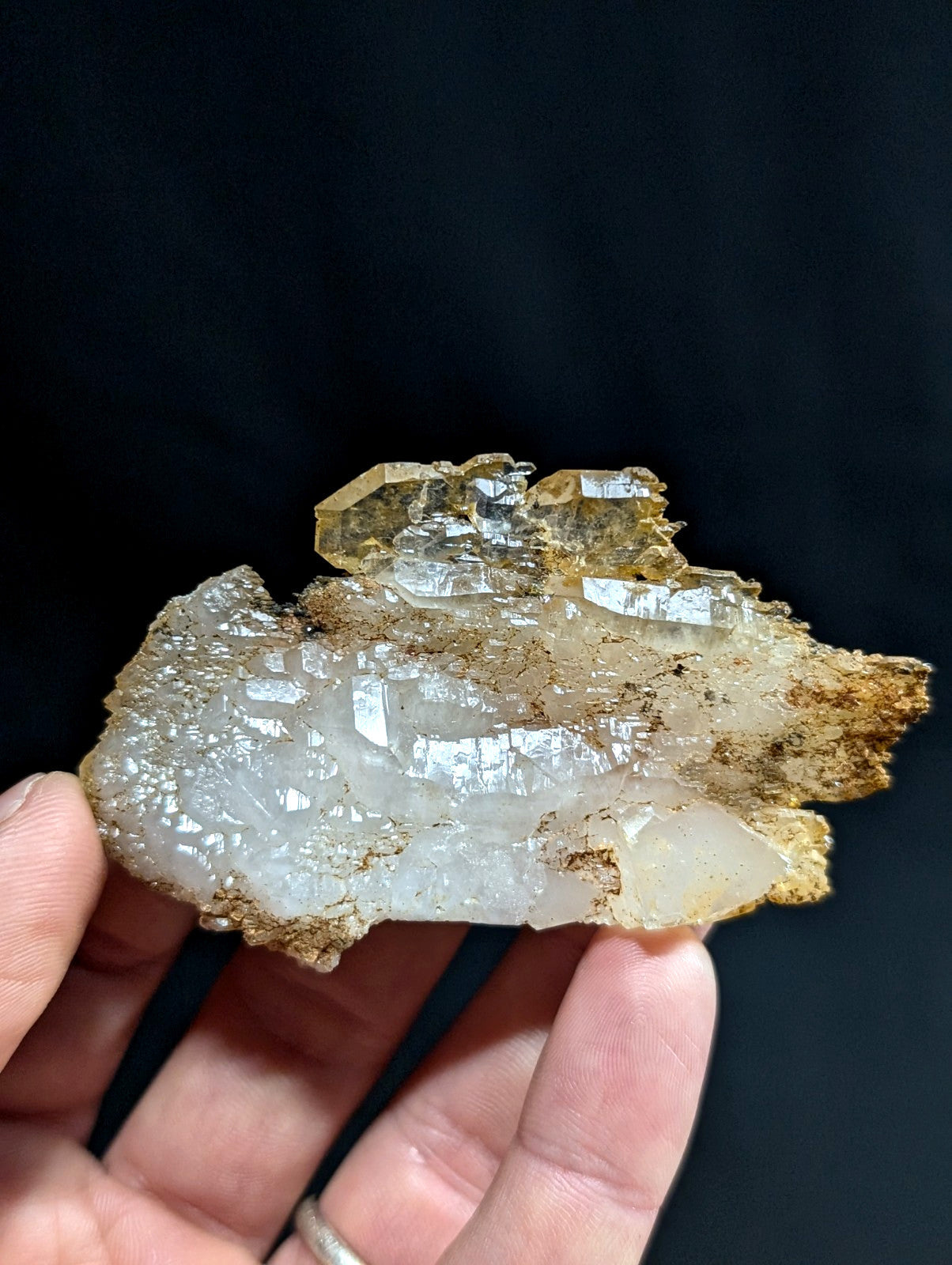 A translucent, crystalline mineral specimen with clear and golden-yellow quartz formations set against a rough, earthy matrix.