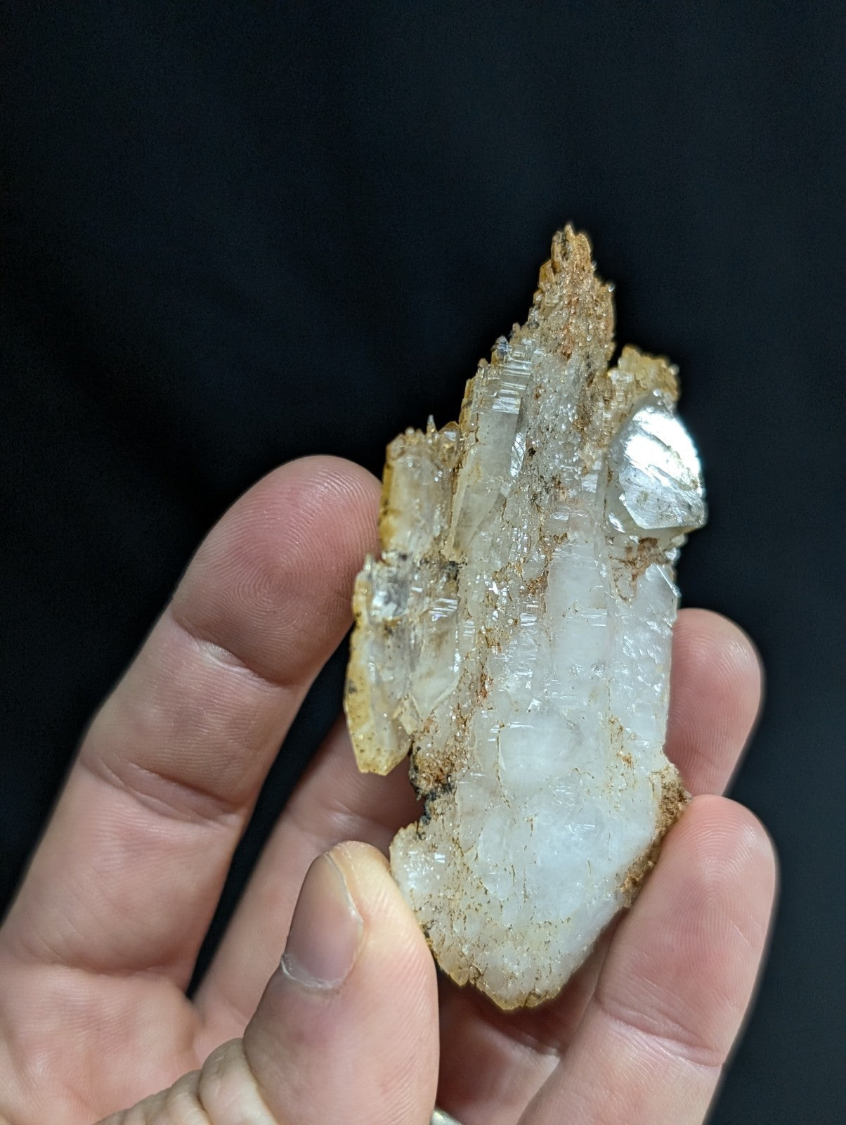 A translucent, crystalline mineral specimen with a mix of clear and milky white quartz crystals embedded in a rough, earthy brown matrix.