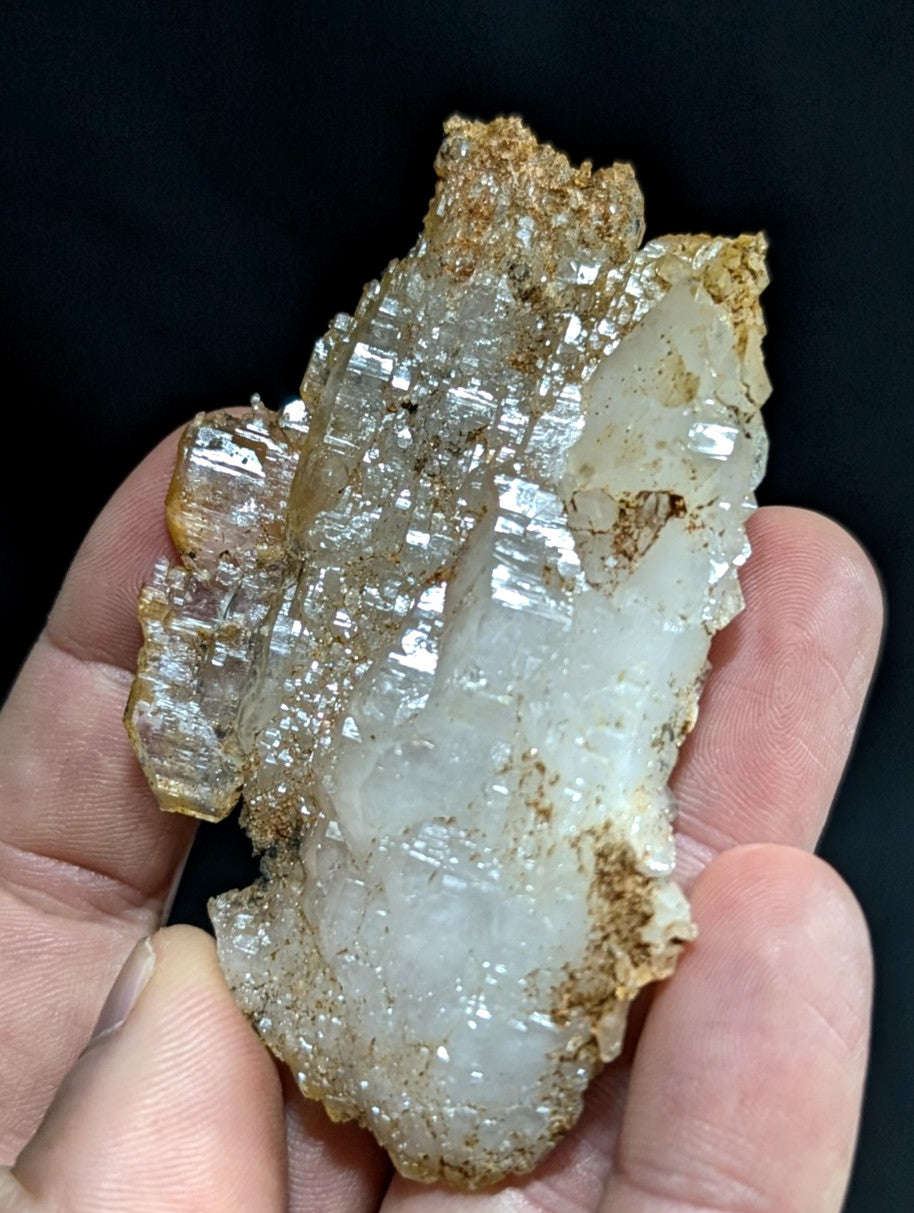 A translucent, crystalline mineral specimen with a mix of clear and milky white sections, accented by golden-brown matrix material.