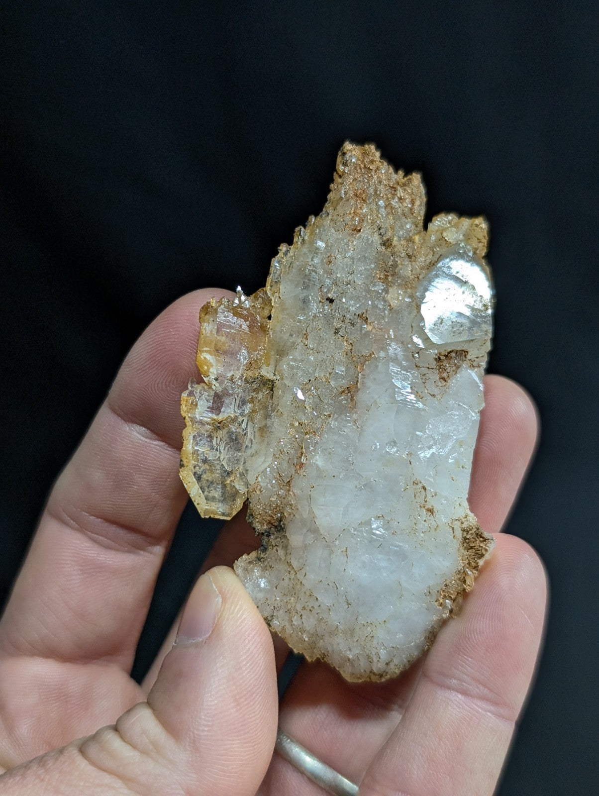 A translucent white quartz crystal cluster with golden-brown matrix and a metallic silver inclusion.