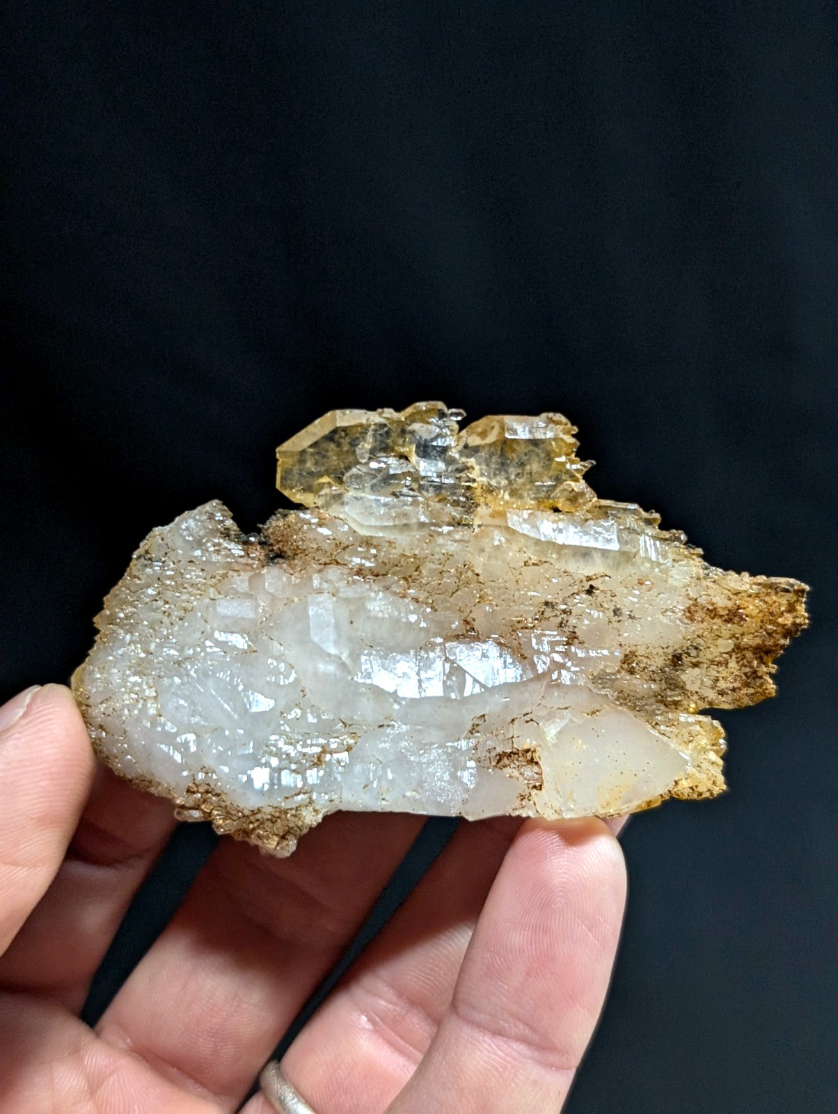 A translucent, crystalline mineral specimen with a mix of clear and milky white facets, accented by golden-brown matrix material along its edges.