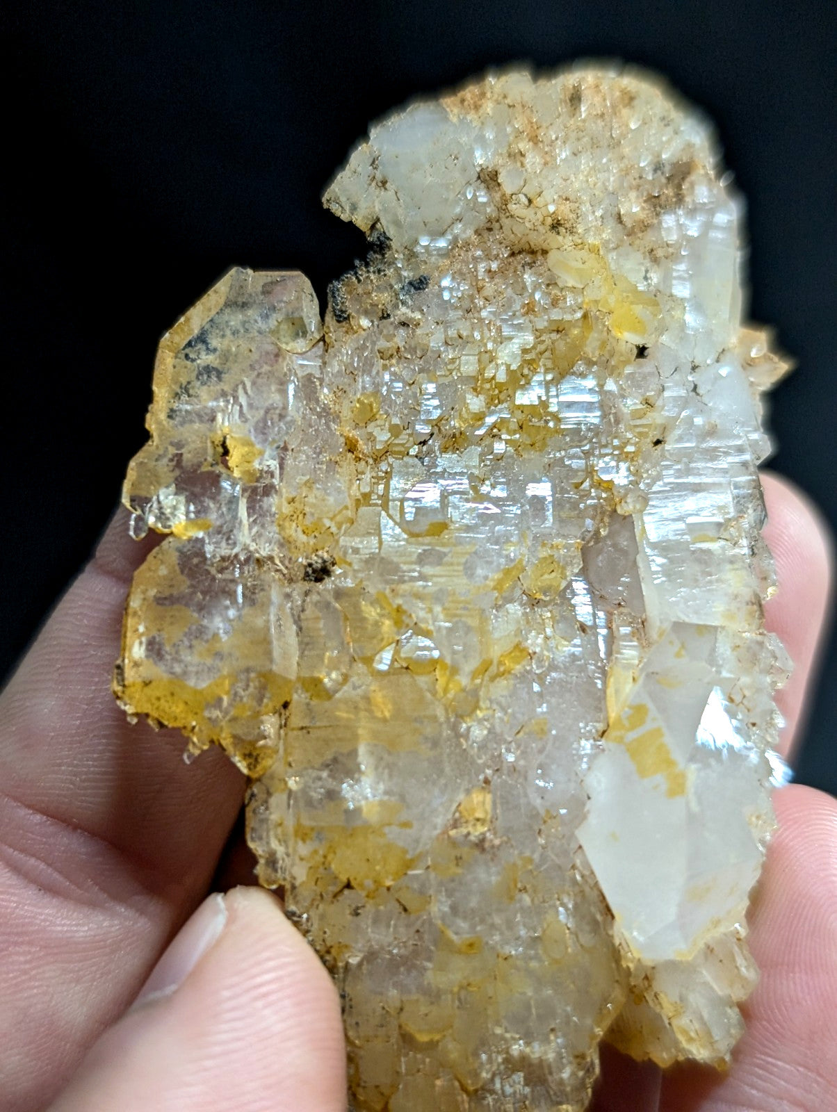 A translucent yellow and white crystal cluster with a rough, jagged surface held in hand.