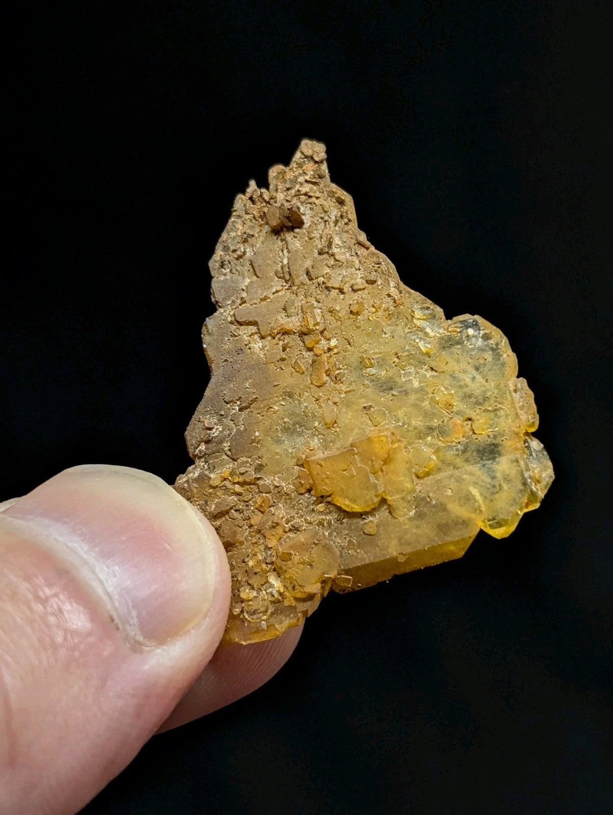 A translucent yellowish mineral specimen with a rough, irregular surface and embedded golden-yellow crystals.