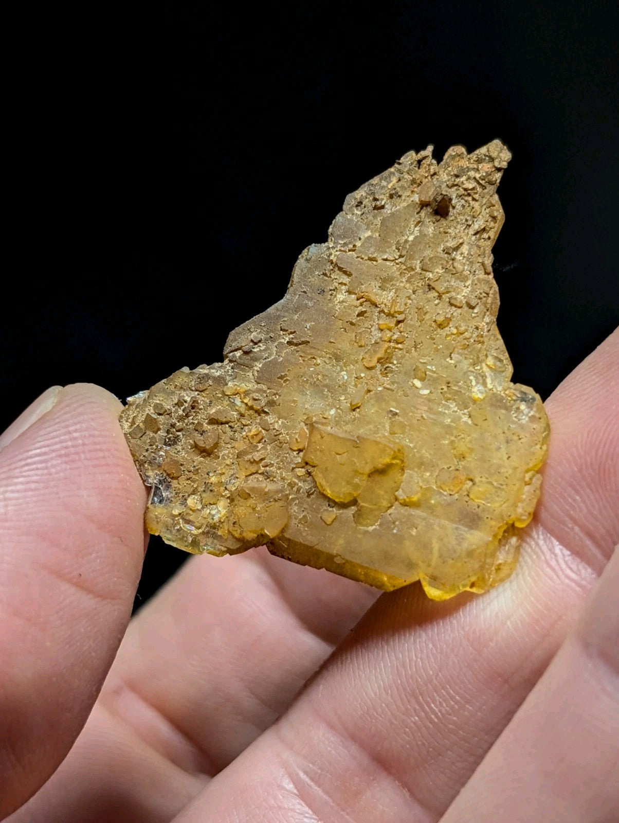 A translucent golden-yellow mineral specimen with a rough, irregular surface and embedded crystalline formations.