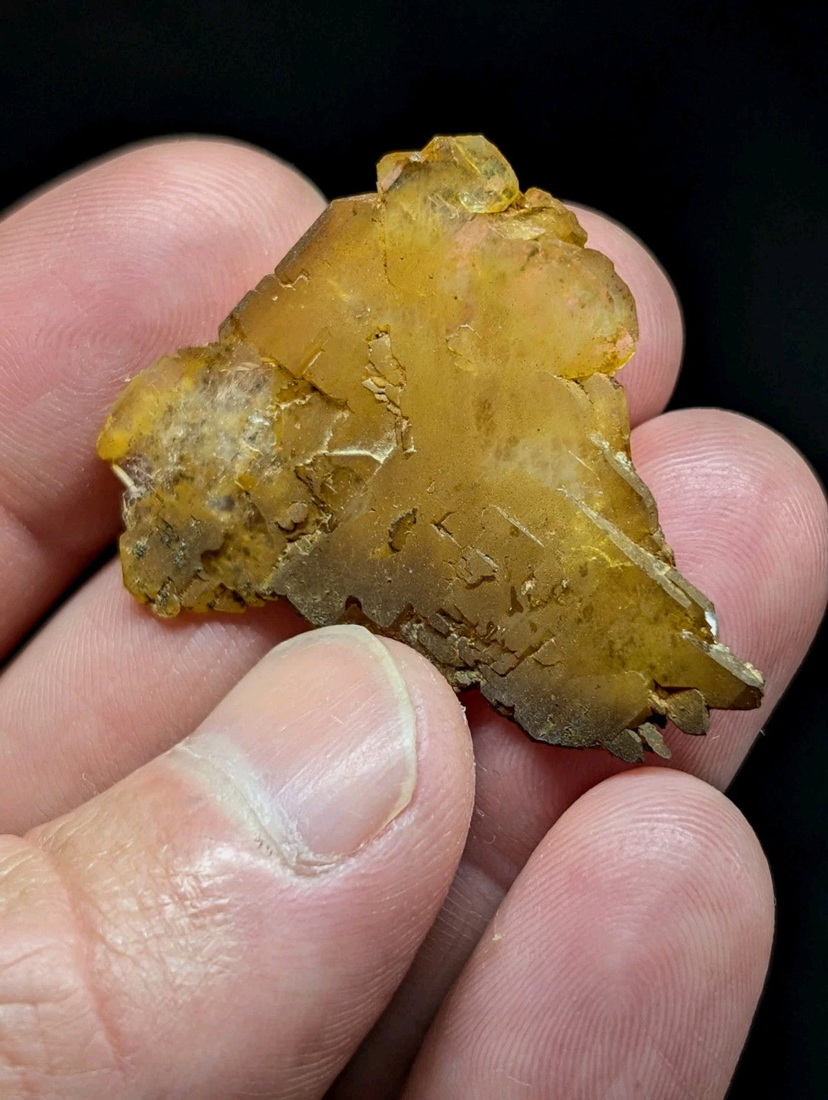 A translucent amber-colored mineral specimen with a rough, irregular surface and visible internal crystalline structures.