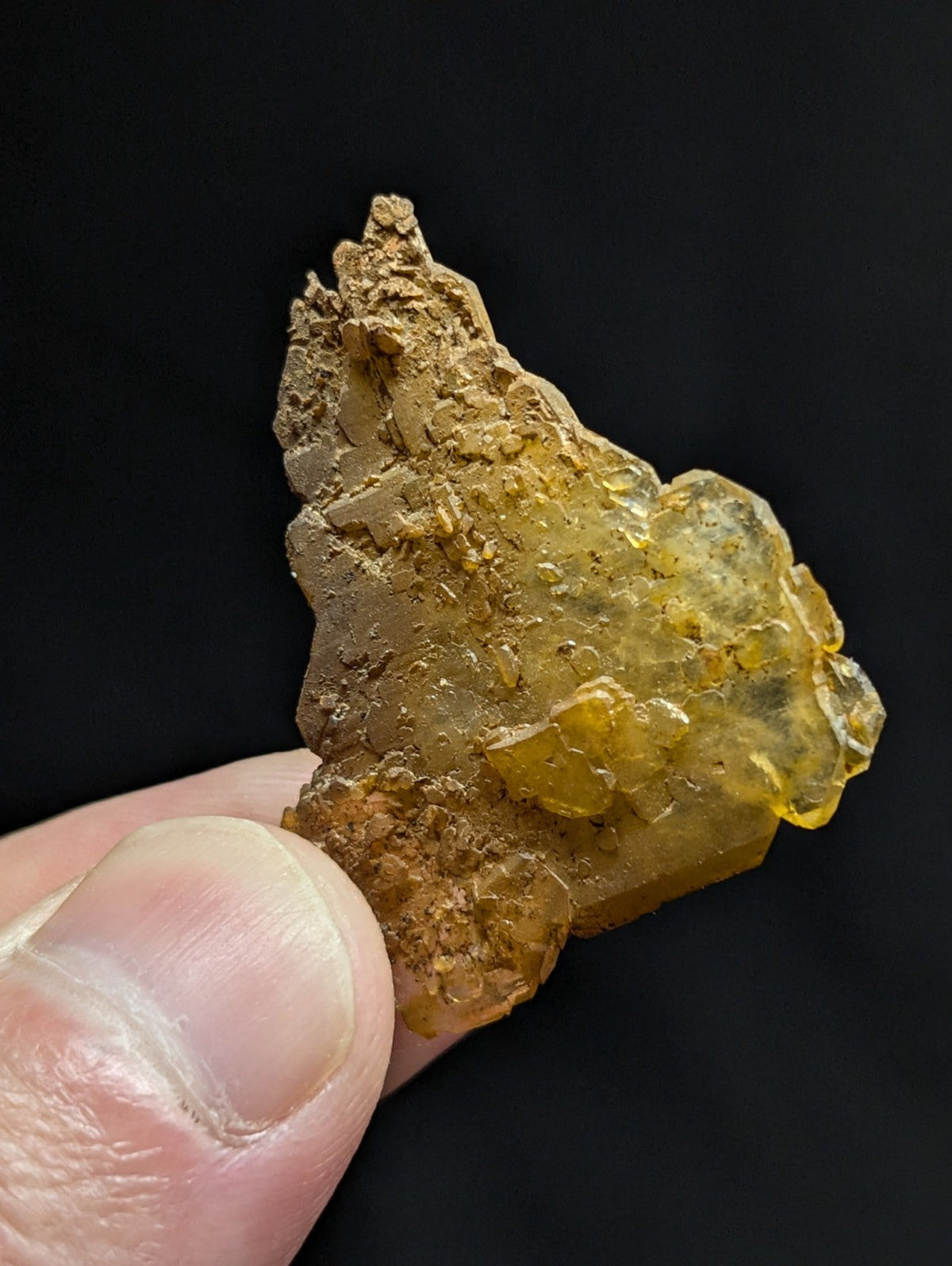 A translucent amber-colored mineral specimen with a rough, crystalline texture and earthy brown patches.
