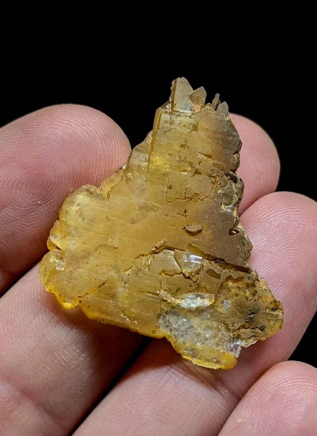 A translucent golden-yellow mineral specimen with jagged, crystalline edges and a rough, natural surface texture.