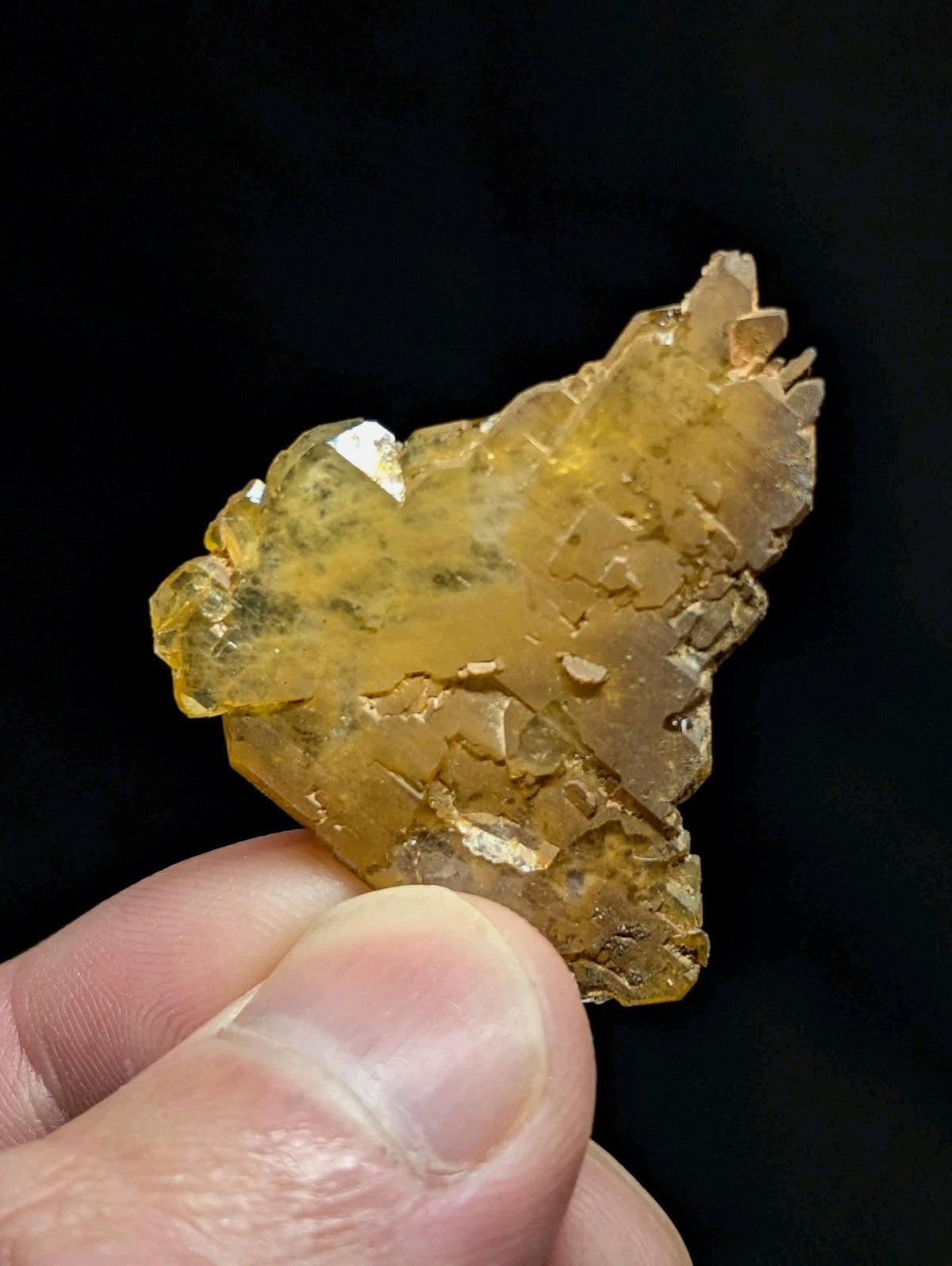 A translucent golden-yellow mineral specimen with jagged, crystalline facets and a rough, natural surface.